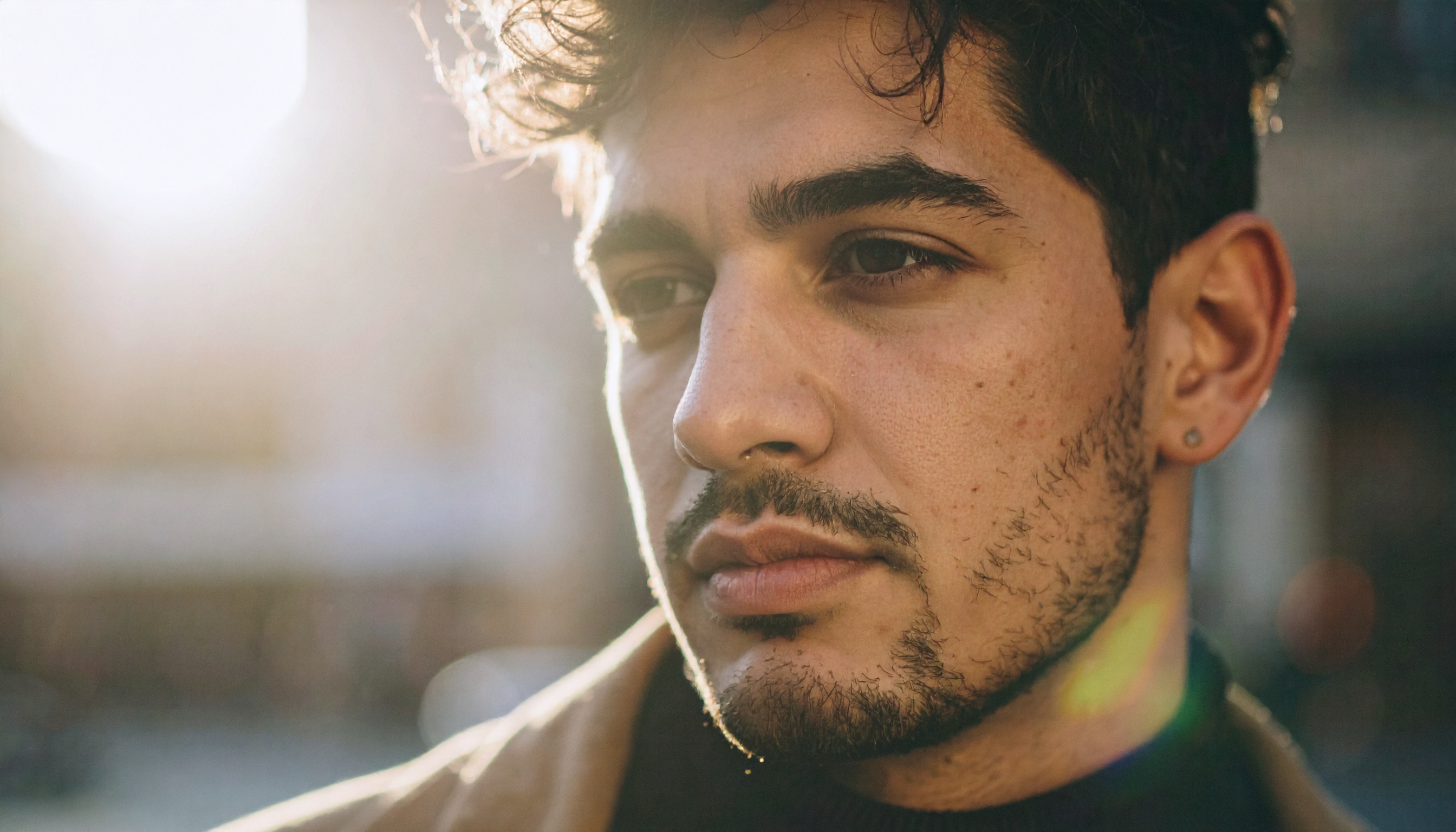 A man gazes into the distance with the sun setting behind him