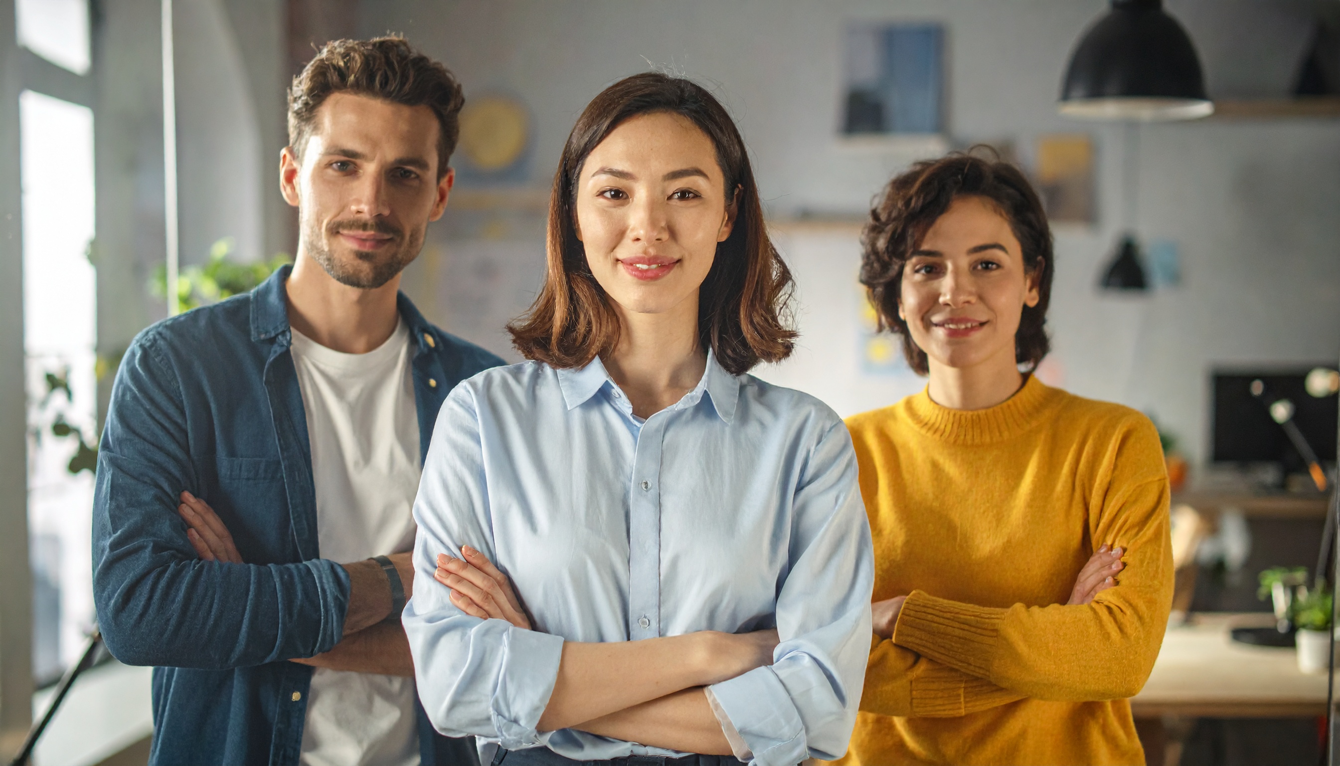 Three professionals stand confidently in an office environment
