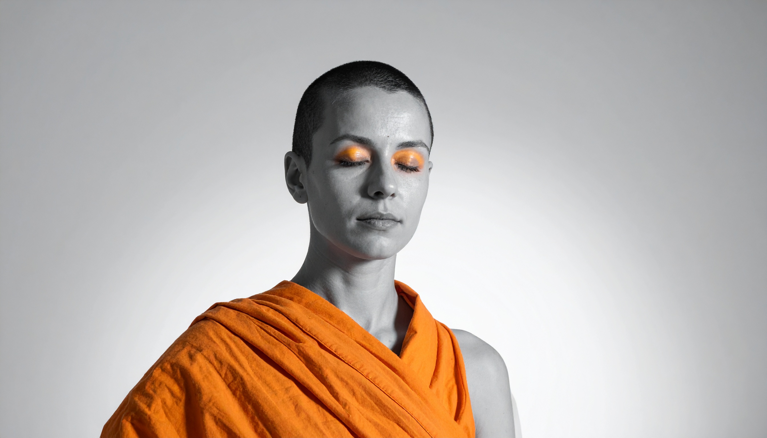 A serene individual in vibrant orange attire meditates peacefully