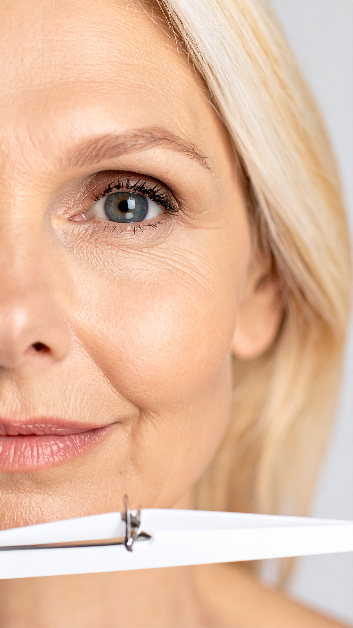 A close-up of a mature woman's face showcases skin texture and eye detail