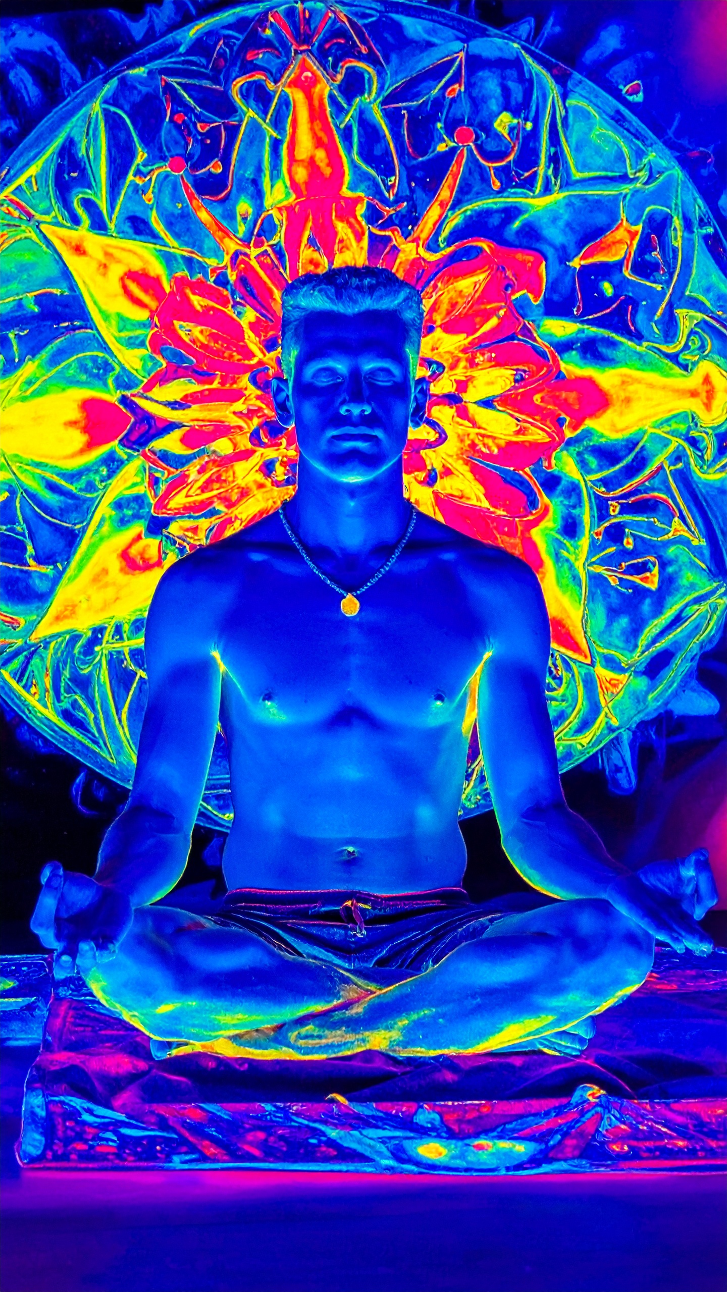 A neon-lit figure sits in a meditative pose against a vibrant mandala backdrop