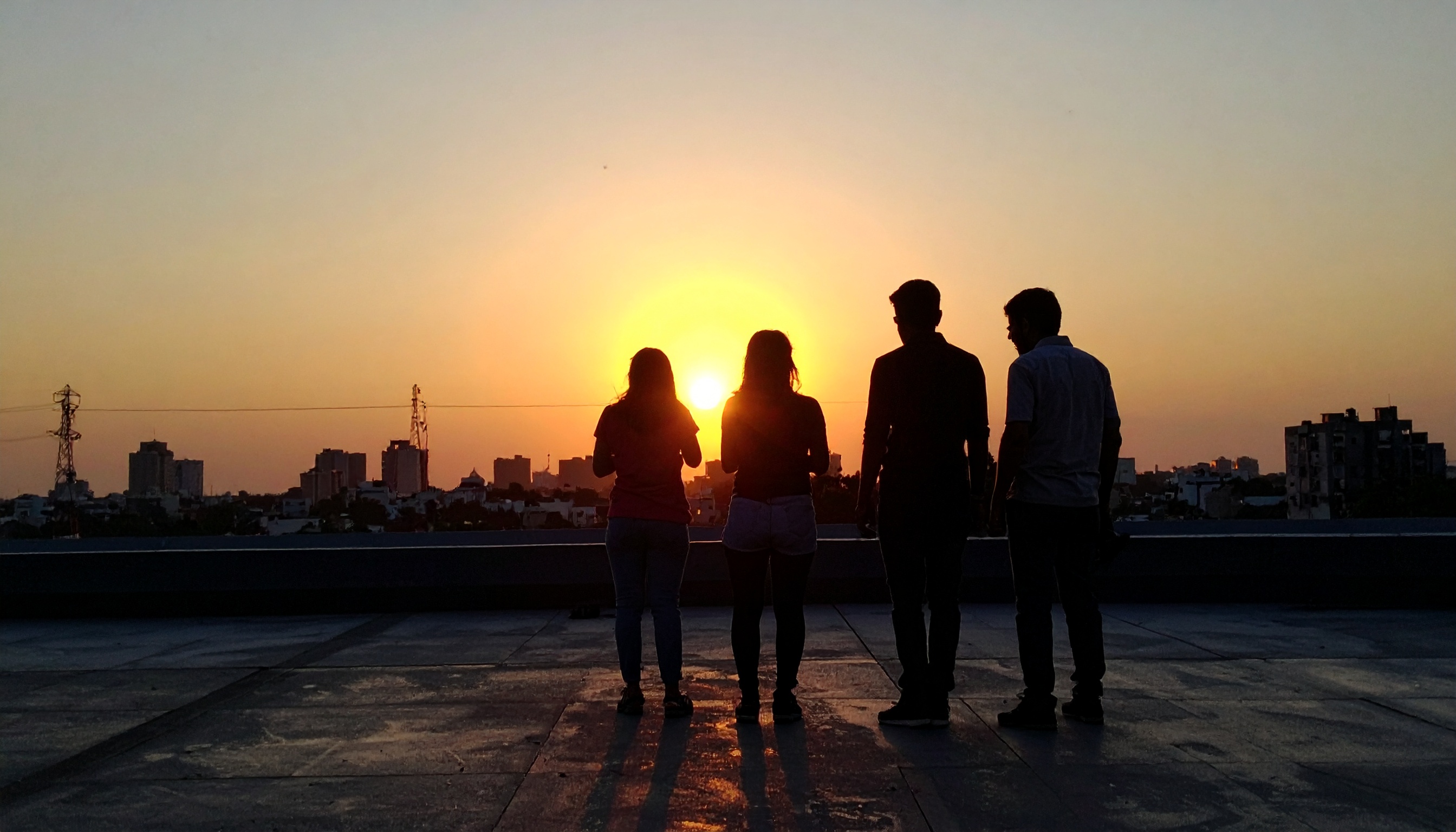 Silhouetted group of four people against a vibrant sunset skyline