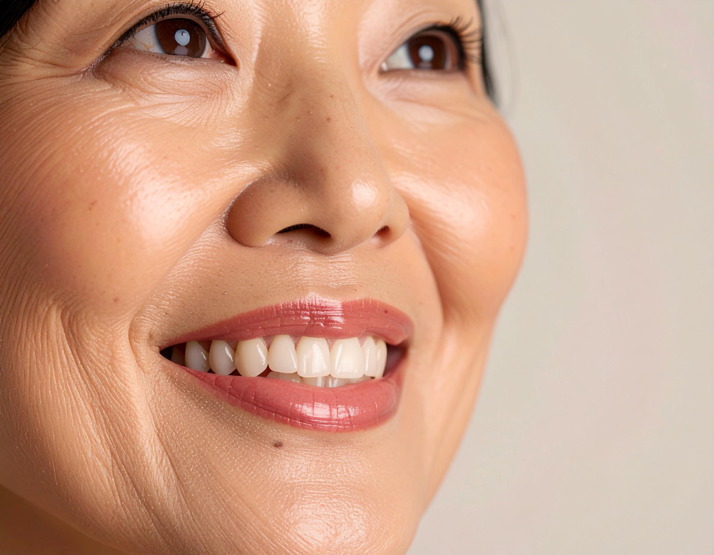 Close-up of a smiling woman highlighting her radiant skin and healthy teeth
