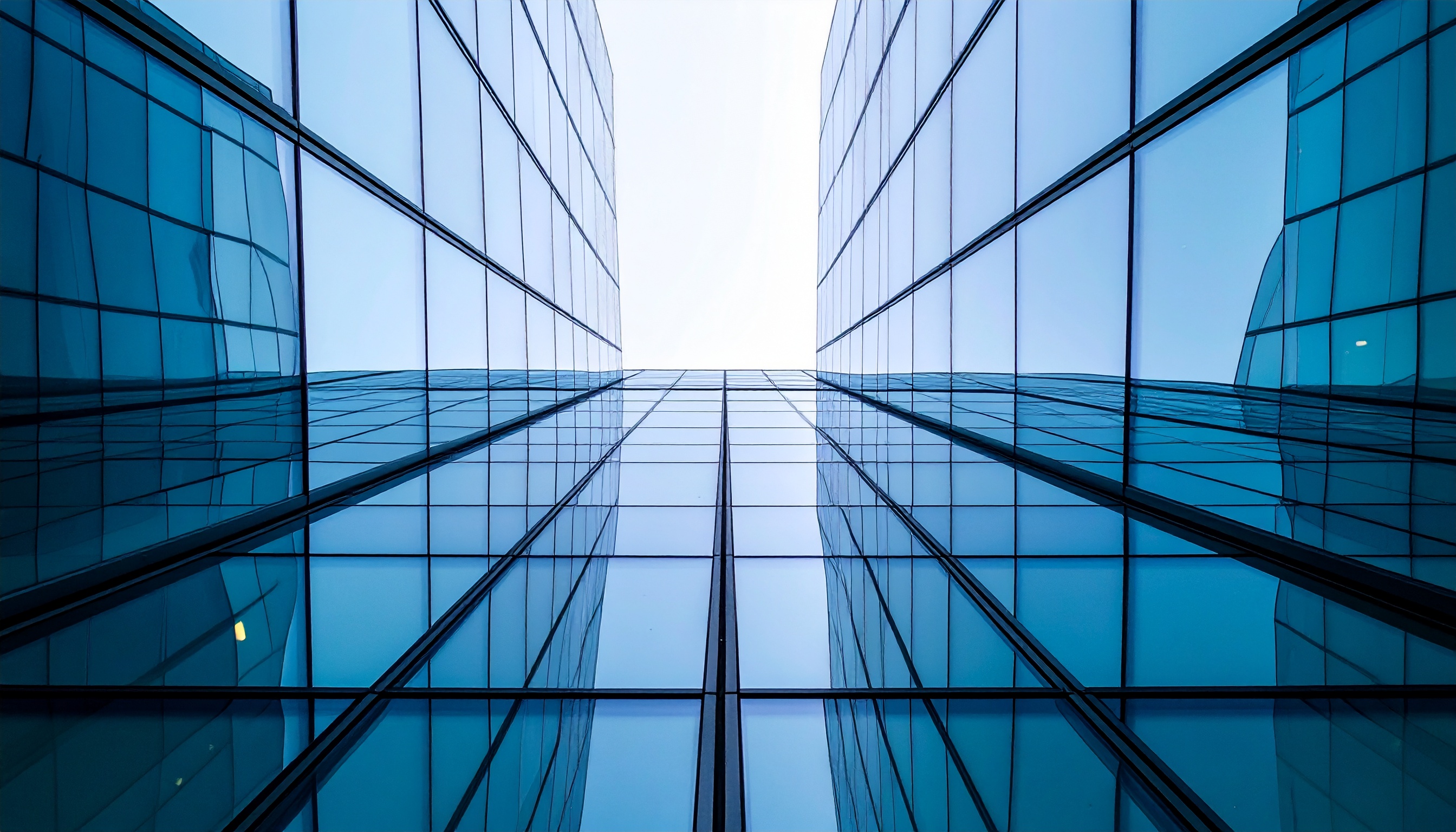 Dramatic Perspective of Two Glass Buildings Reflecting Blue Sky