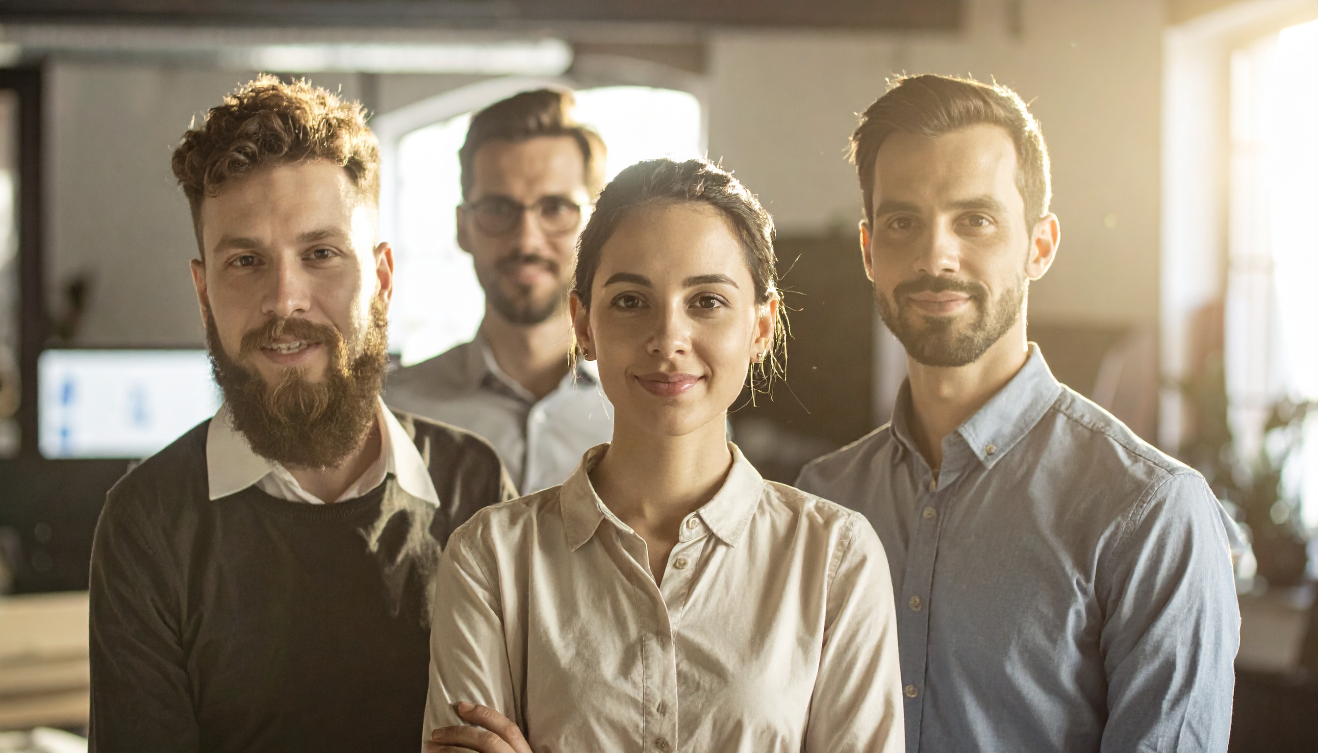 Equipe de jovens profissionais em ambiente de escritório moderno. Ideal para representar colaboração e inovação no ambiente de trabalho. A imagem destaca-se pela iluminação suave e os sorrisos confiantes dos membros da equipe. Perfeita para uso em materiais de marketing corporativo e campanhas de recrutamento. O ambiente transmite uma atmosfera acolhedora e profissional.