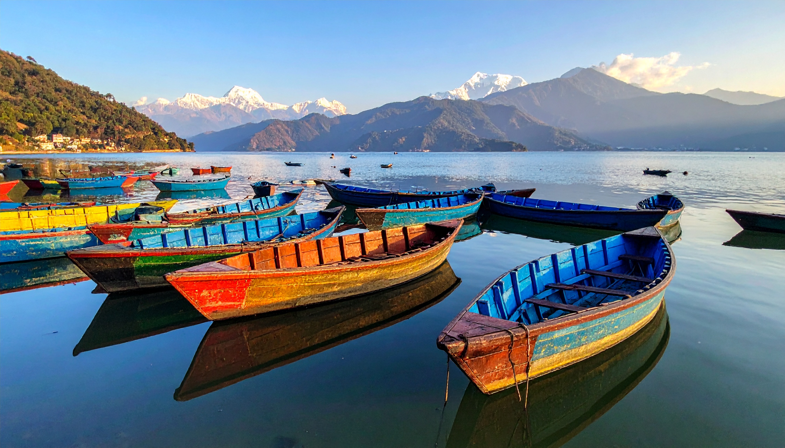 Barcos coloridos flutuam tranquilamente em um lago sereno, cercado por montanhas majestosas. Ideal para promover destinos turísticos ou viagens relaxantes, esta cena evoca paz e beleza natural. As cores vibrantes dos barcos contrastam com o azul suave da água e o branco das montanhas ao fundo. Perfeito para uso em campanhas de turismo, especialmente em regiões montanhosas e lacustres. A imagem transmite uma sensação de tranquilidade e aventura, tornando-a atraente para amantes da natureza.