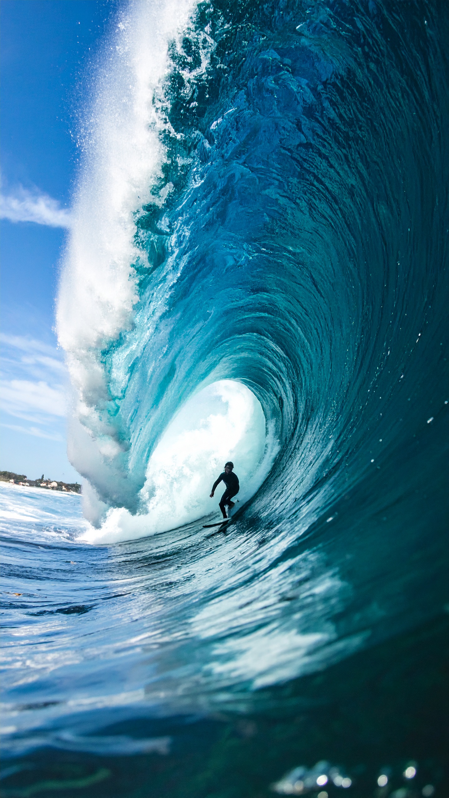 A surfer skillfully rides inside a massive ocean wave, showcasing the thrill of extreme water sports