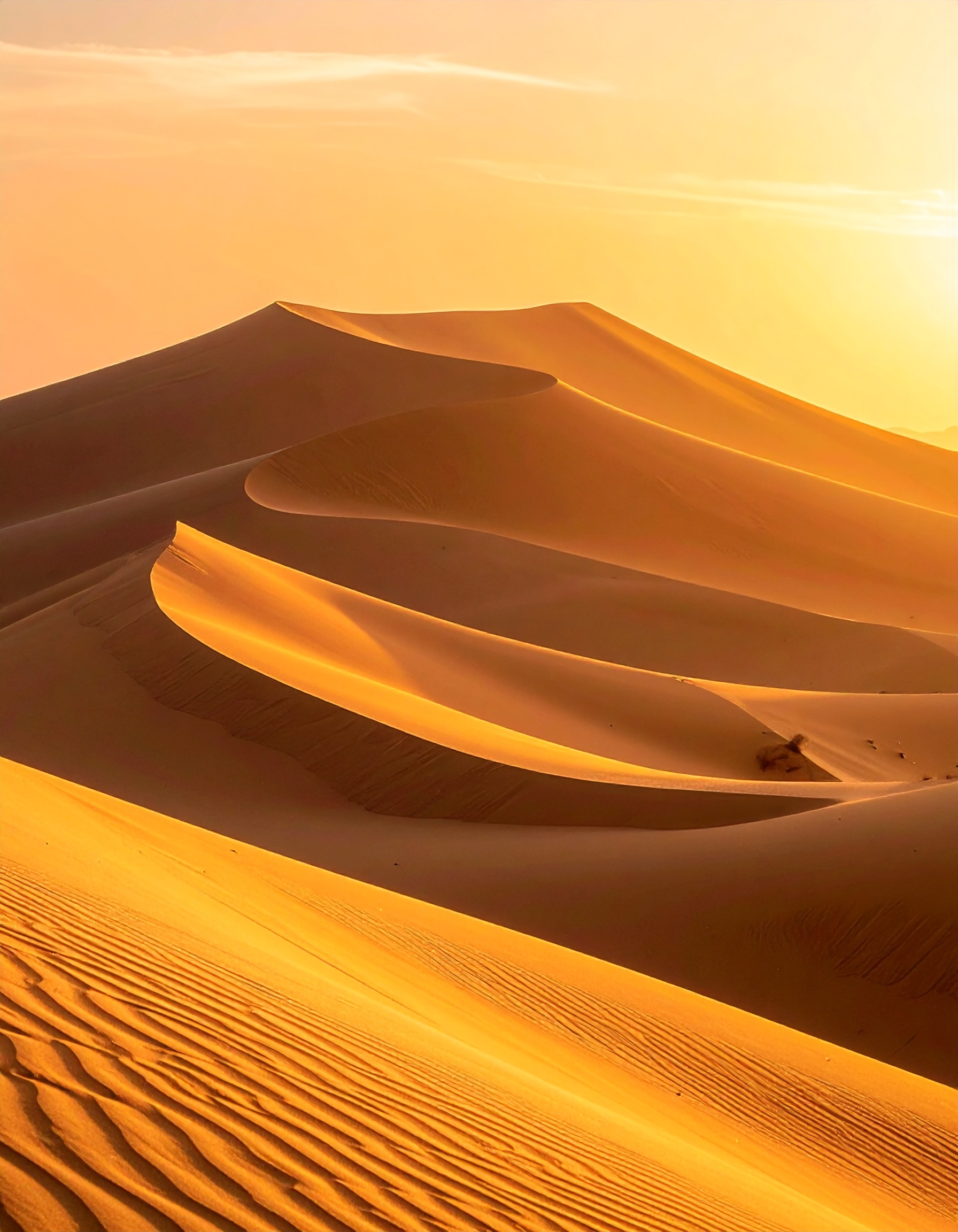 Golden sand dunes under a vibrant sunset create a mesmerizing desert landscape