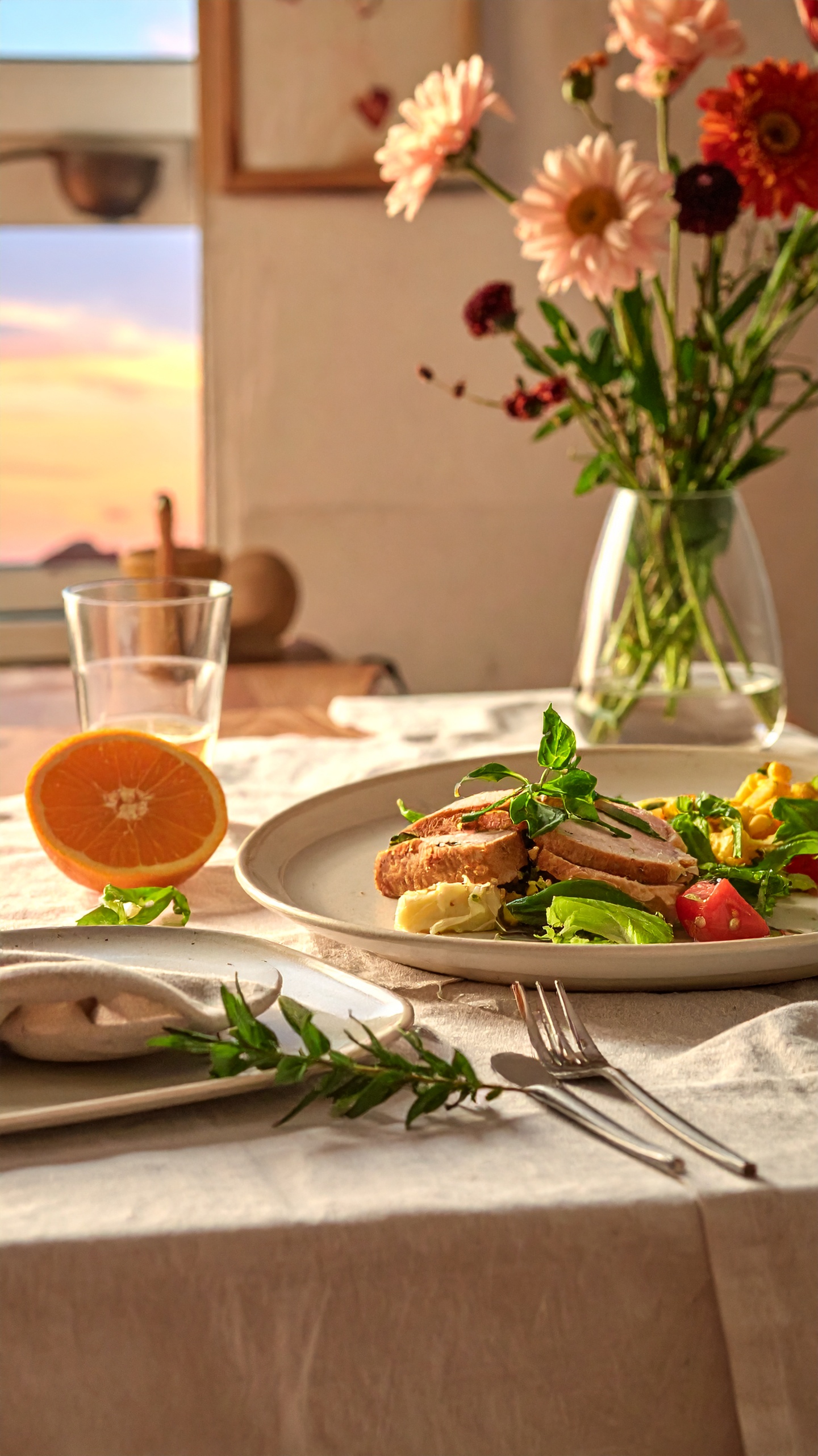 A beautifully arranged dining table features a plate with gourmet food, including sliced meat, fresh