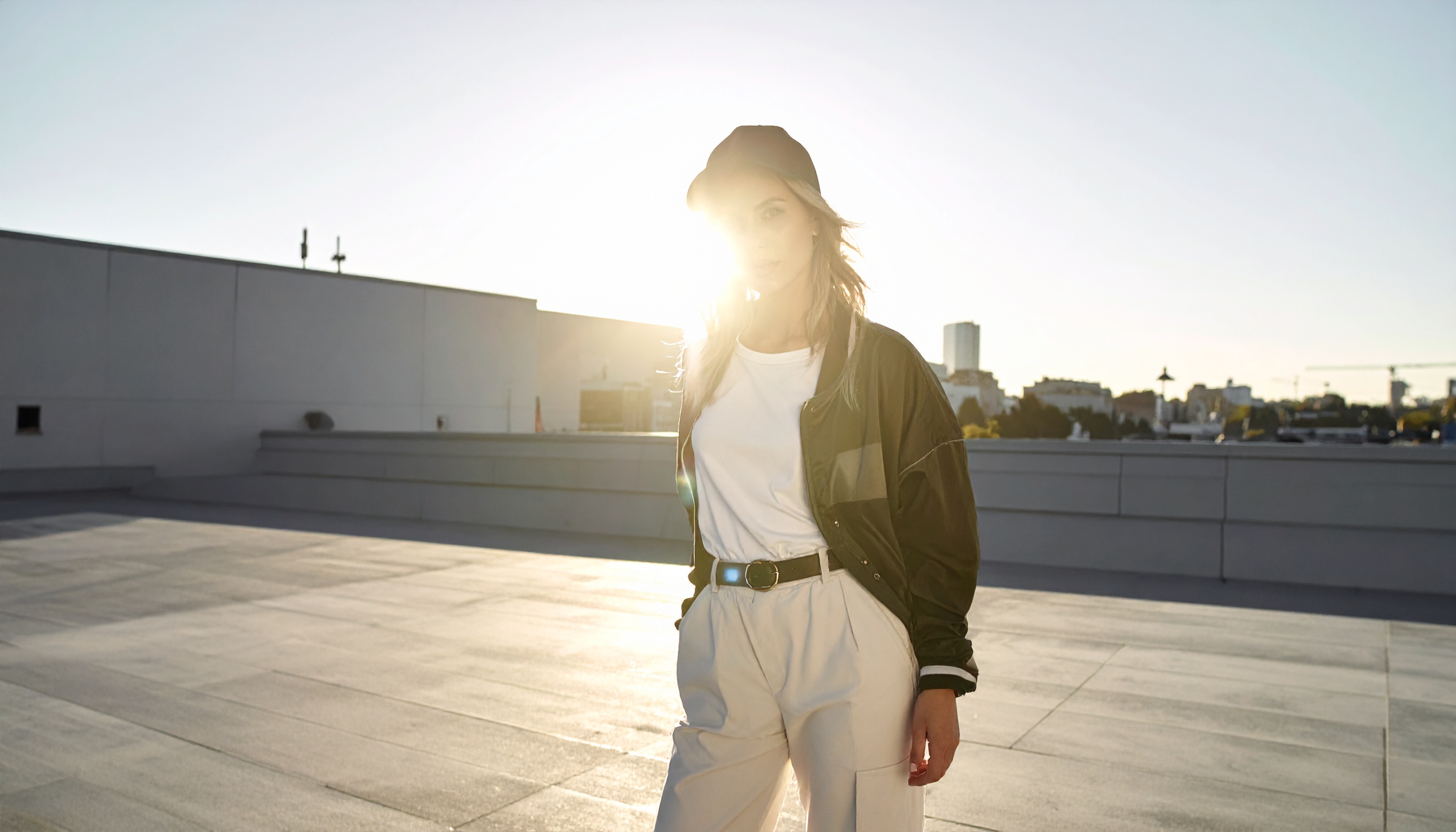 A imagem mostra uma jovem em um telhado urbano ao pôr do sol, criando uma atmosfera moderna e descolada. Essa cena é perfeita para campanhas de moda ou marketing urbano, destacando um estilo casual e contemporâneo. A luz do sol ao fundo destaca a silhueta e adiciona um toque artístico à composição. Esse tipo de imagem é ideal para uso em redes sociais e materiais promocionais que visam captar a atenção do público jovem. O contraste entre o cenário urbano e a iluminação natural oferece uma sensação de liberdade e espontaneidade.