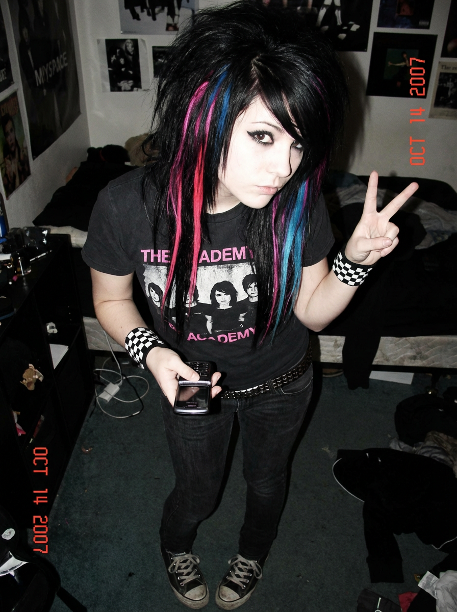 A young person poses with a peace sign in a room with a vibrant emo style