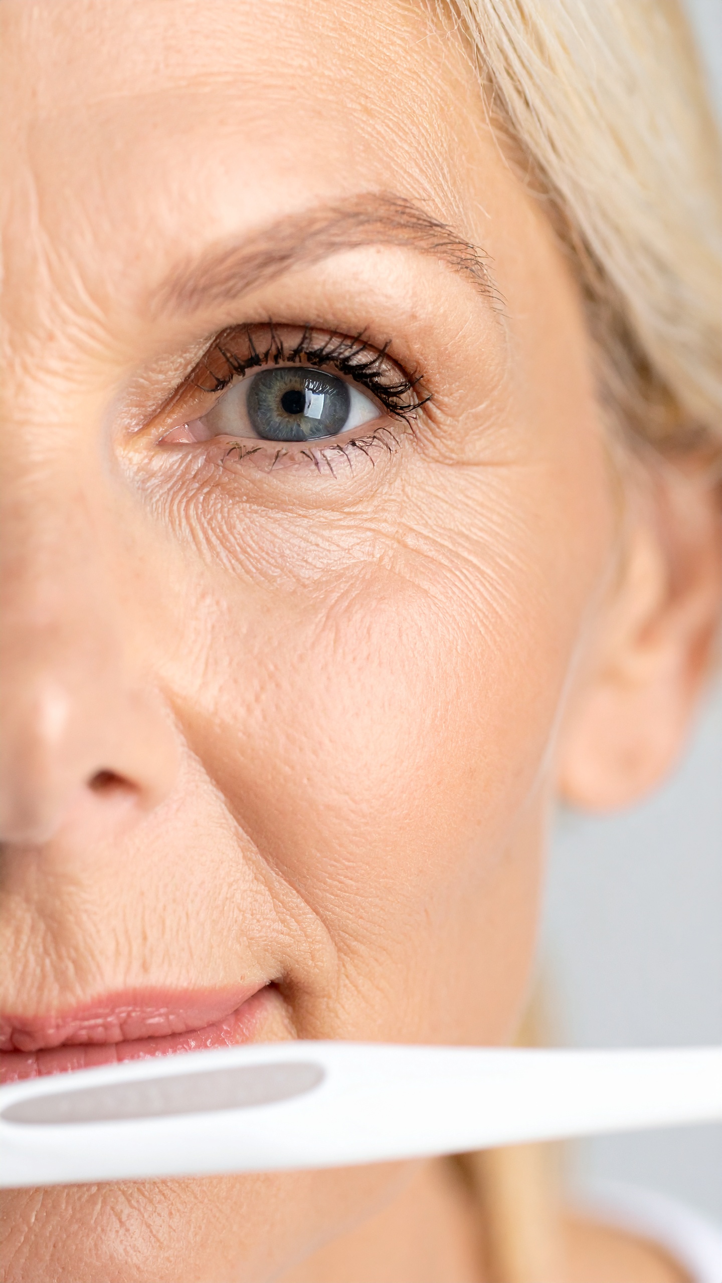 Close-up of a woman holding a thermometer near her lips