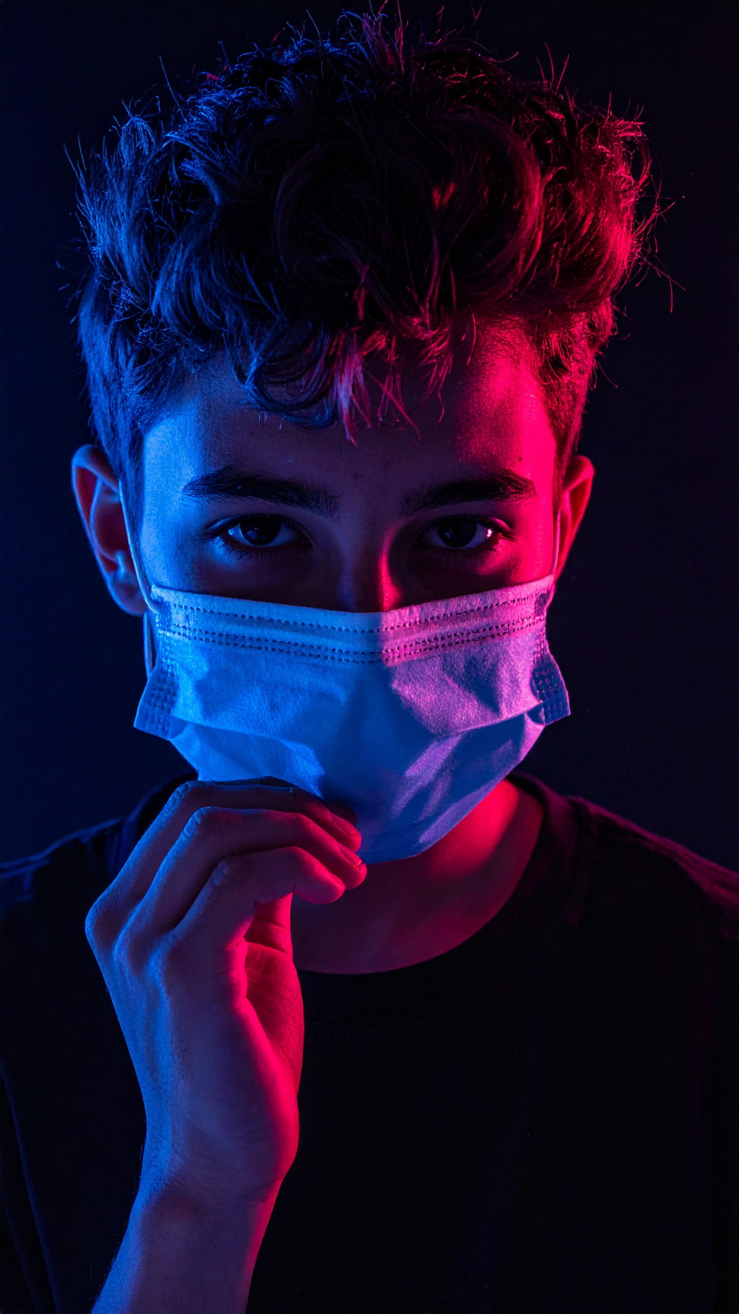 Teen wearing a face mask under red and blue lighting