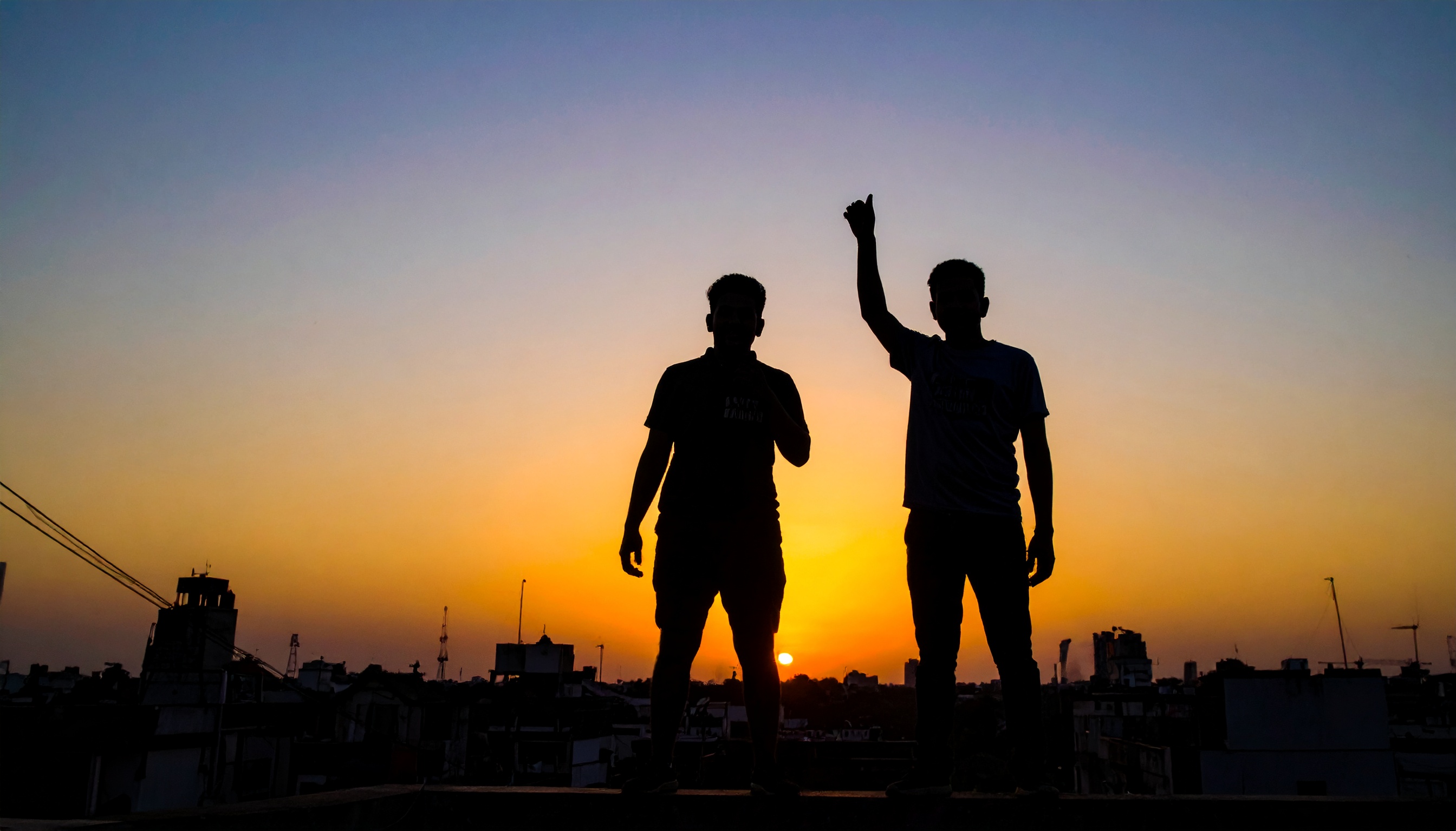 Silhouetted figures stand against a vibrant sunset