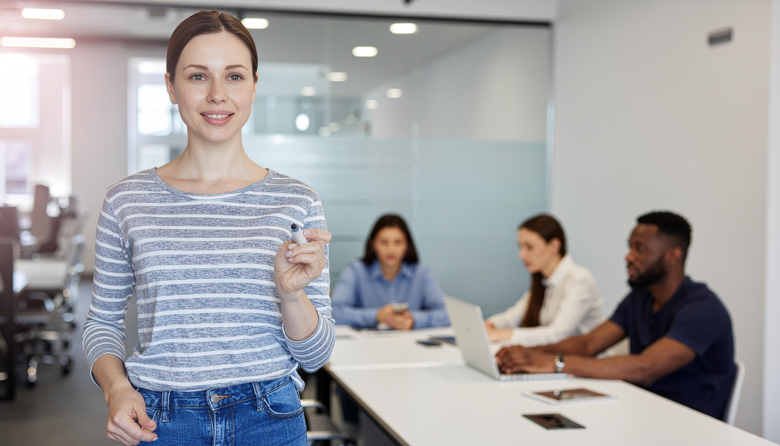 Woman in Focus in Bright Meeting Room Holding a Pen