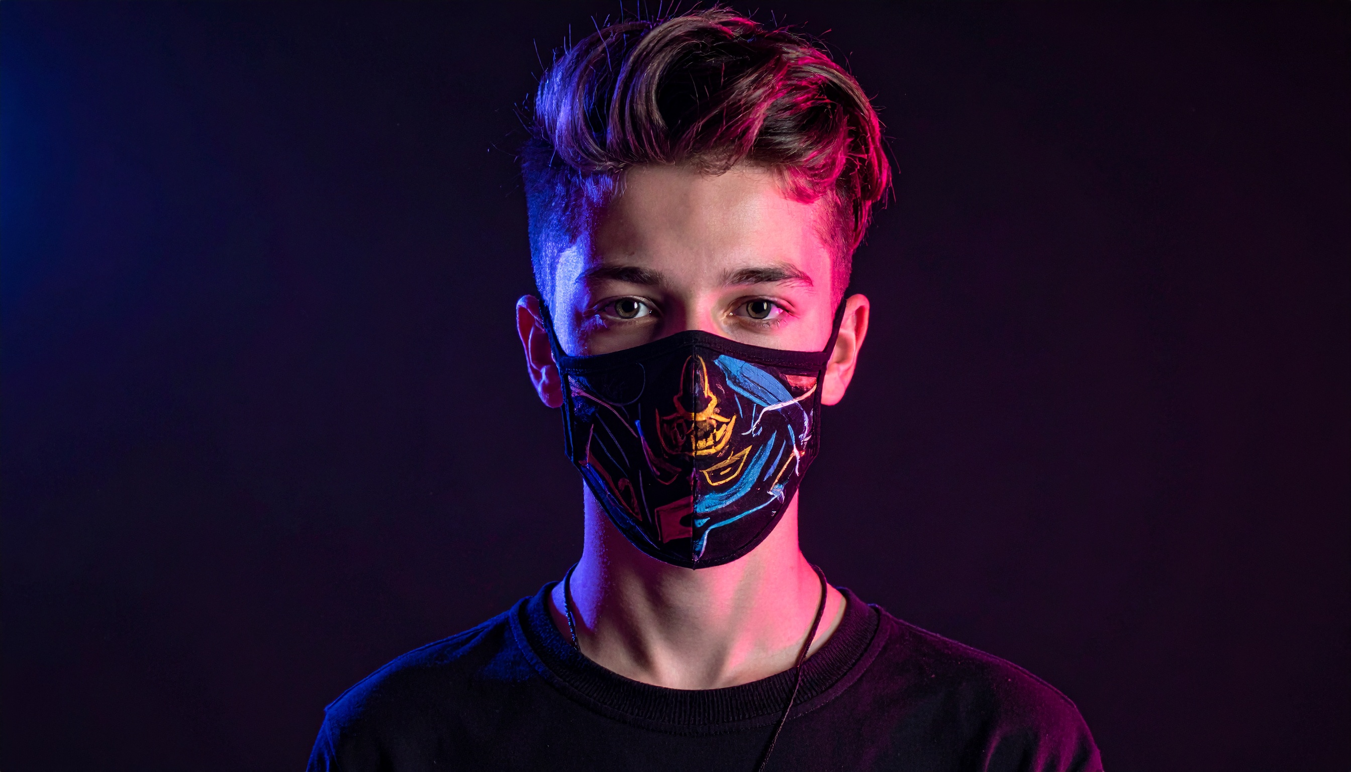 A young man wears a fashionable face mask with a striking graphic design, set against