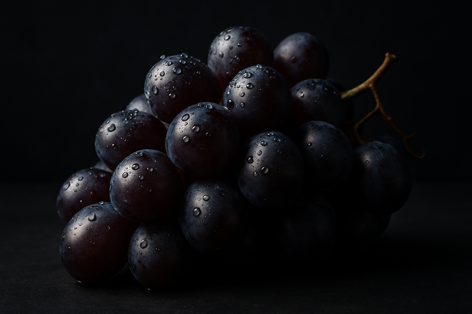Cacho de uvas escuras com gotas de água sobre fundo preto. Ideal para uso em campanhas de marketing de alimentos frescos e saudáveis. As uvas, com suas gotas de água, destacam-se pela sua textura e cor intensa. Perfeitas para promover produtos em ambientes sofisticados e elegantes. A imagem transmite frescor e qualidade, ideal para atrair consumidores em lojas gourmet.