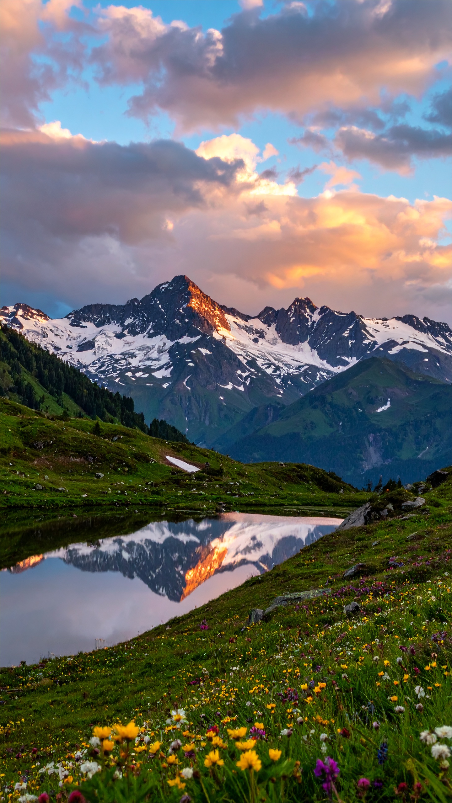 A breathtaking mountain landscape features a snow-capped peak reflecting in a serene lake