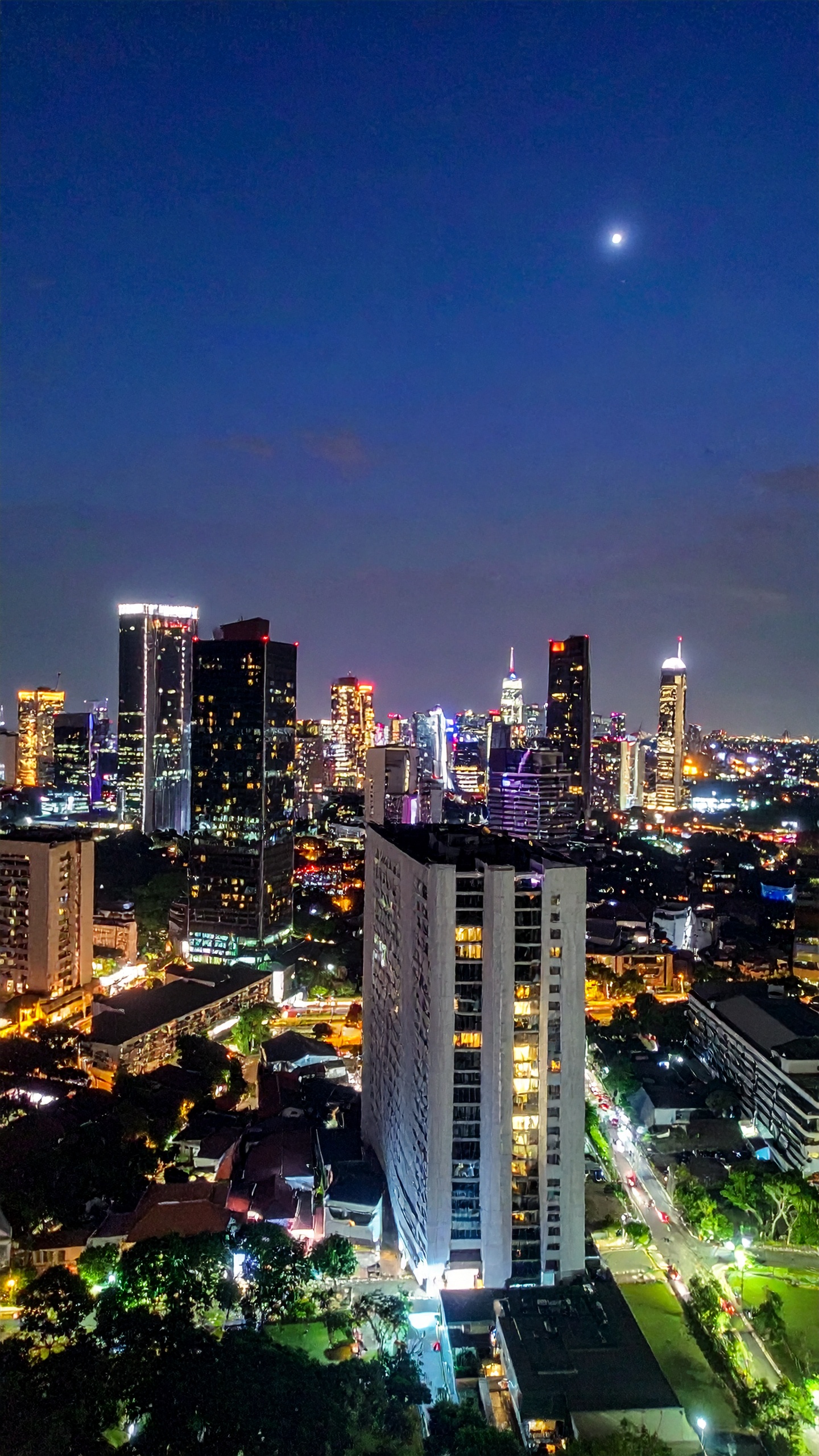 A vibrant city skyline glows under a twilight sky, illuminated by numerous skyscrapers