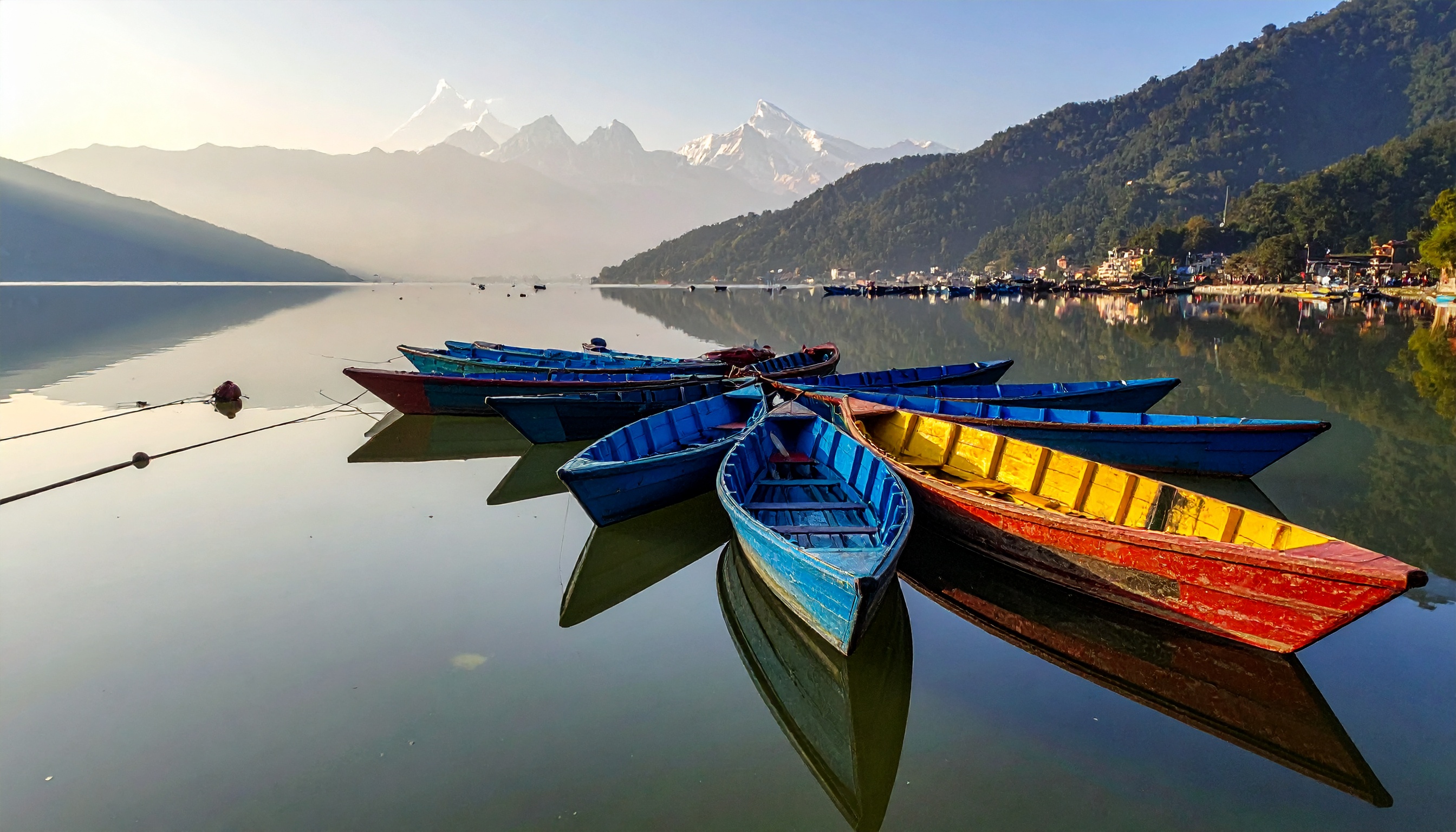 Barcos coloridos flutuam calmamente em um lago sereno cercado por montanhas majestosas. Ideais para passeios turísticos, eles oferecem uma experiência tranquila e pitoresca. O reflexo das embarcações na água espelhada realça a beleza natural do ambiente. Este cenário é perfeito para atividades ao ar livre e fotografia, especialmente ao amanhecer. A combinação de cores vibrantes e paisagem montanhosa cria uma atmosfera de tranquilidade e inspiração.