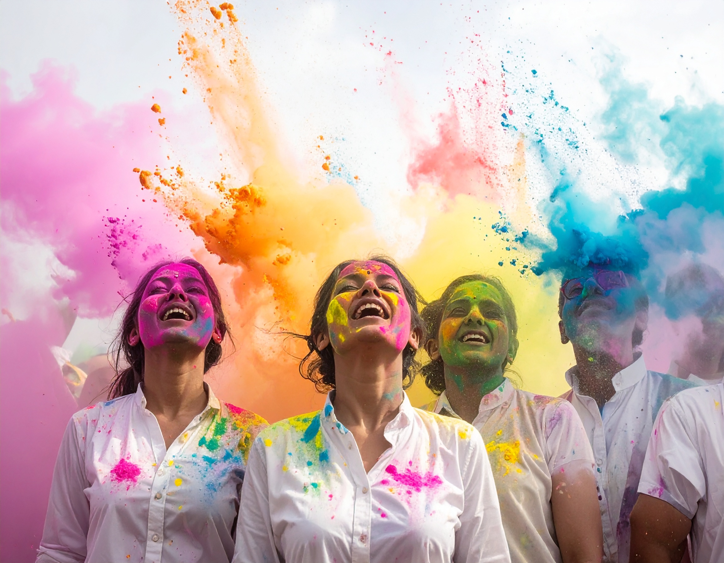 A group of people joyfully celebrating with vibrant colored powders