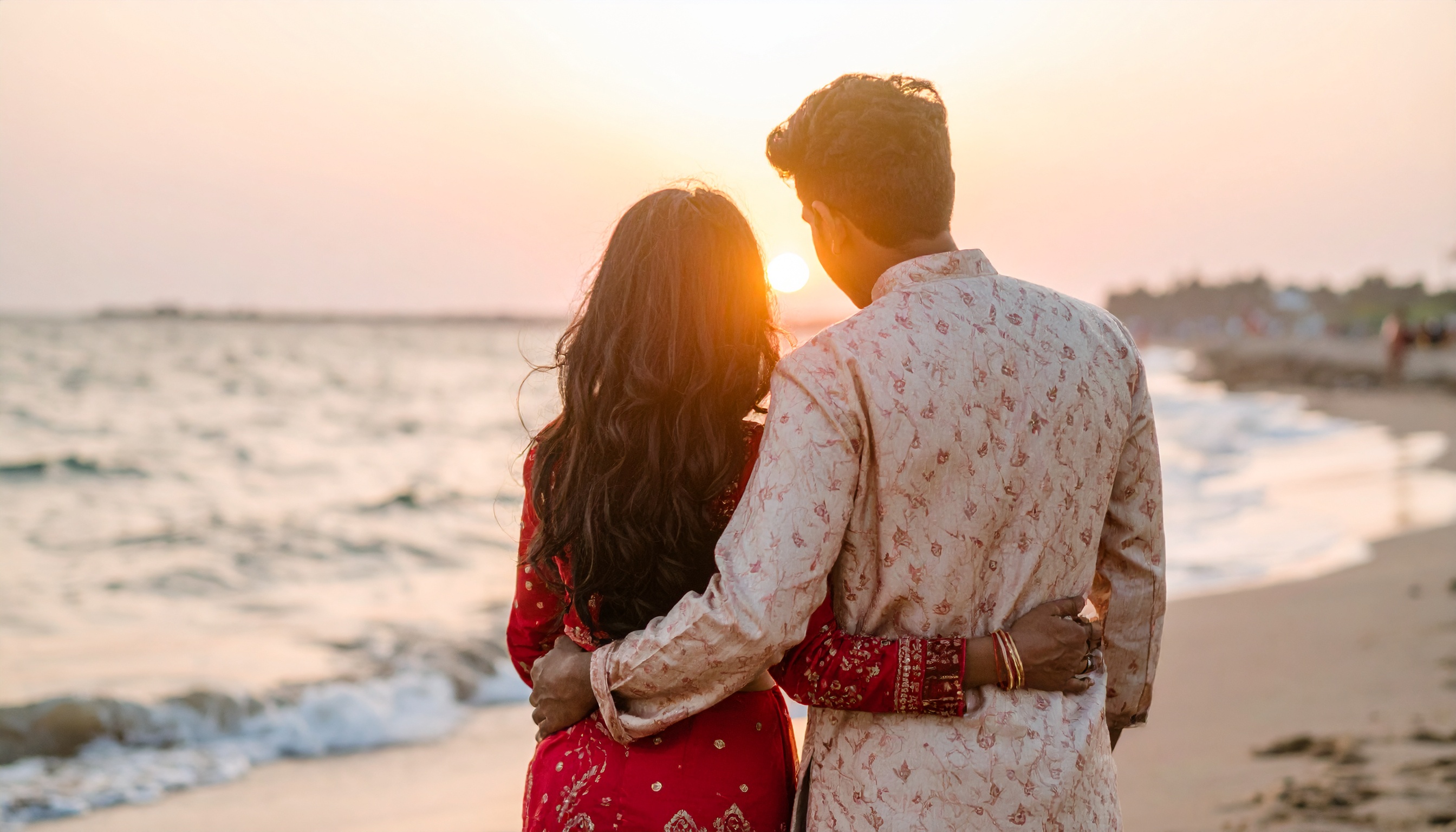 A couple embraces on a beach at sunset, embodying romance and tranquility