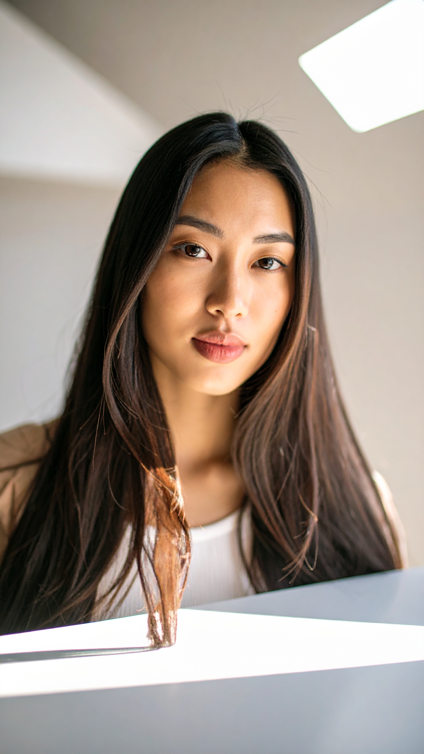 A young woman with long hair is captured in soft lighting, giving a serene and natural vibe
