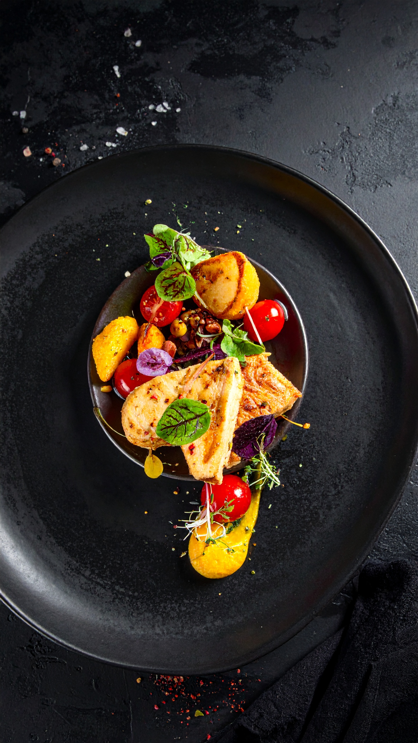 A gourmet dish artfully presented on a sleek black plate