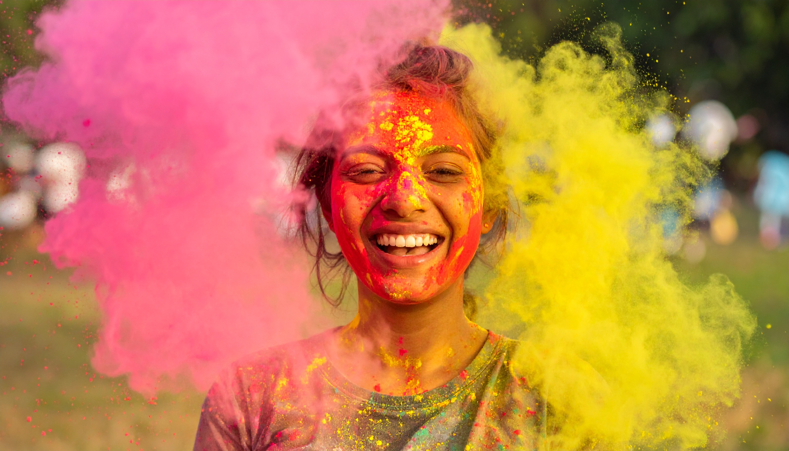 A joyful person celebrates with vibrant colored powders in a festival setting