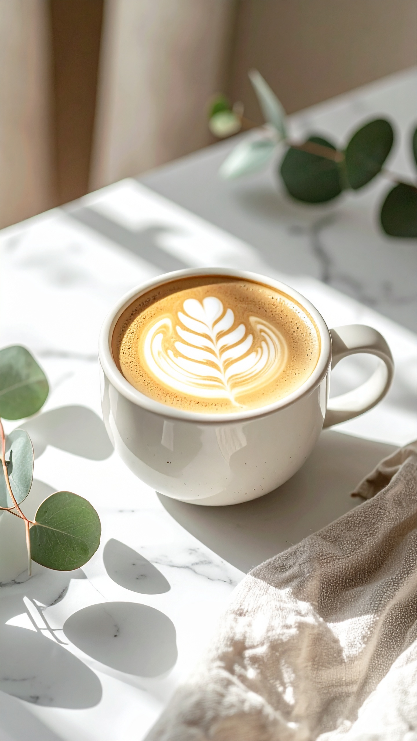 A beautifully crafted latte with intricate foam art sits on a white marble surface
