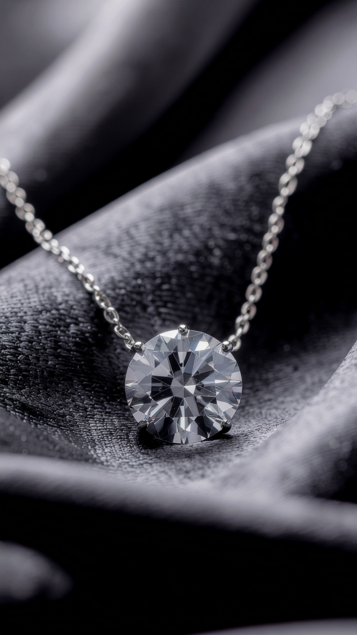 Colar com corrente de prata destacando um deslumbrante diamante lapidado sobre um fundo de tecido escuro. Iluminação suave ressalta o brilho e os detalhes do corte da pedra preciosa, criando um contraste elegante com a textura do tecido em um ângulo macro.