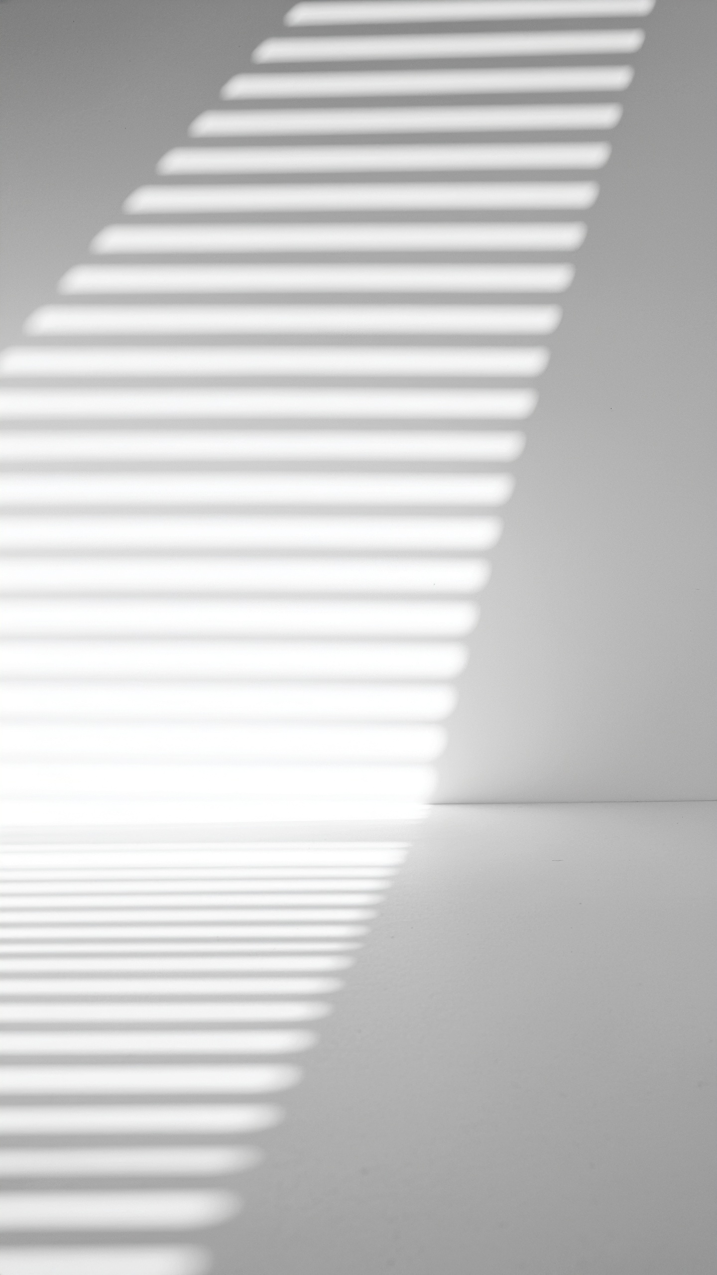 Diagonal shadow stripes cast on a white wall create a minimalist visual effect