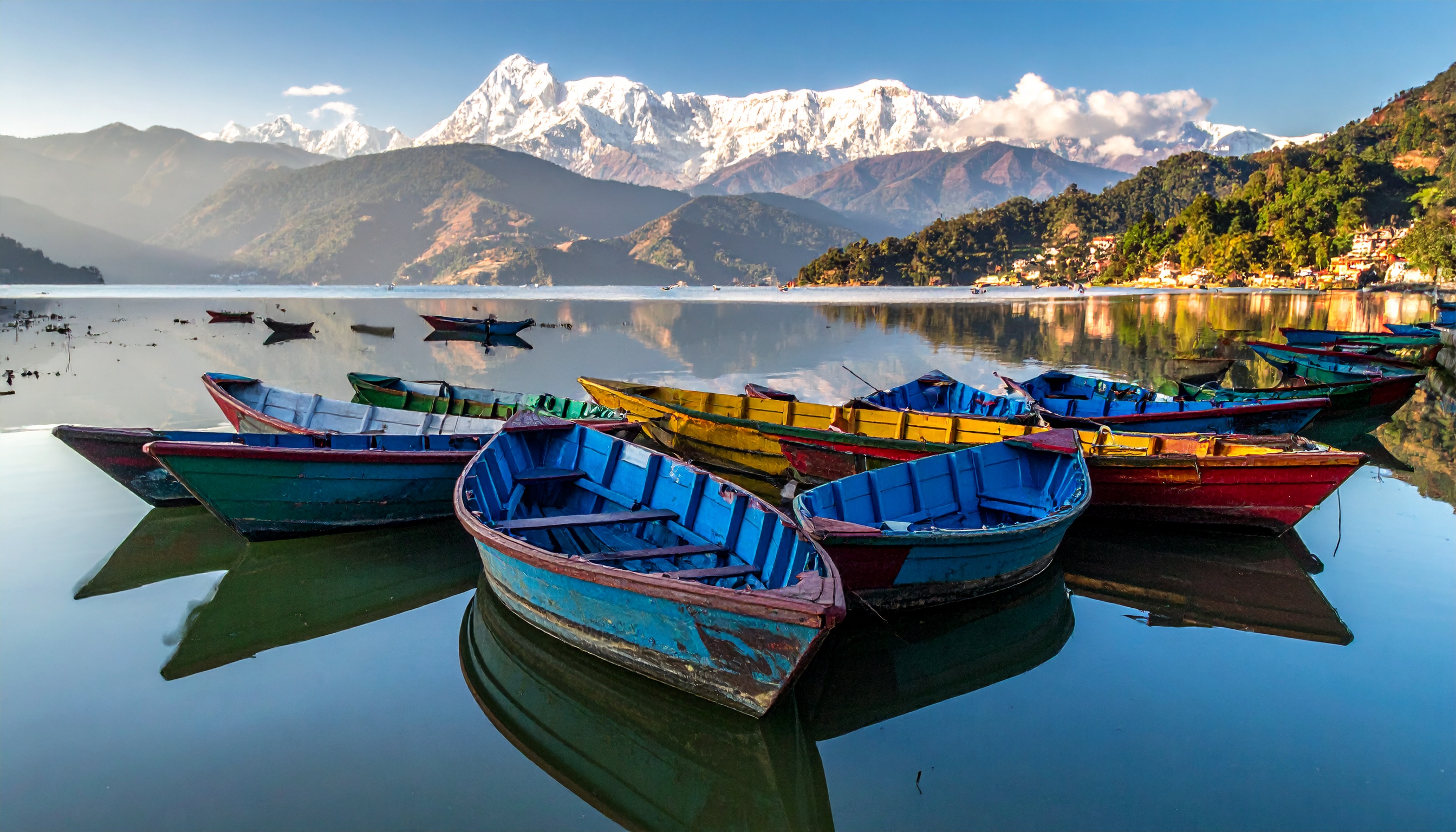 Barcos coloridos flutuam serenamente em um lago cristalino, cercado por montanhas majestosas cobertas de neve. Ideal para promoções de turismo e produtos relacionados à viagem, a imagem evoca tranquilidade e aventura. As cores vibrantes dos barcos contrastam com a calma azul do lago, criando uma composição visualmente atraente. Ótima escolha para campanhas de marketing durante a primavera ou o verão, quando tais paisagens são mais procuradas. A cena transmite uma sensação de escapismo e conexão com a natureza, valorizando experiências ao ar livre.