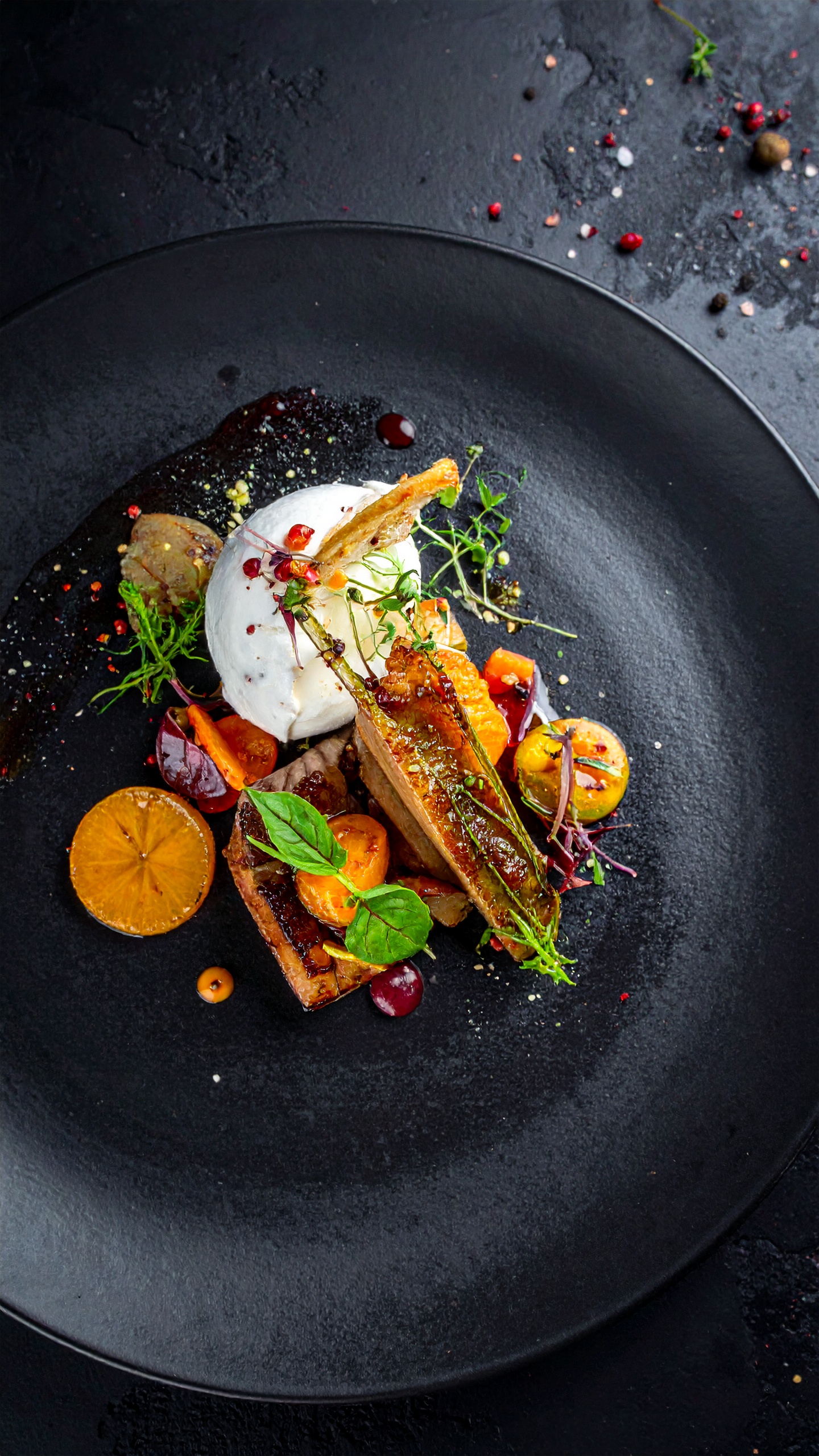 A gourmet dish beautifully arranged on a black plate, showcasing a sophisticated presentation