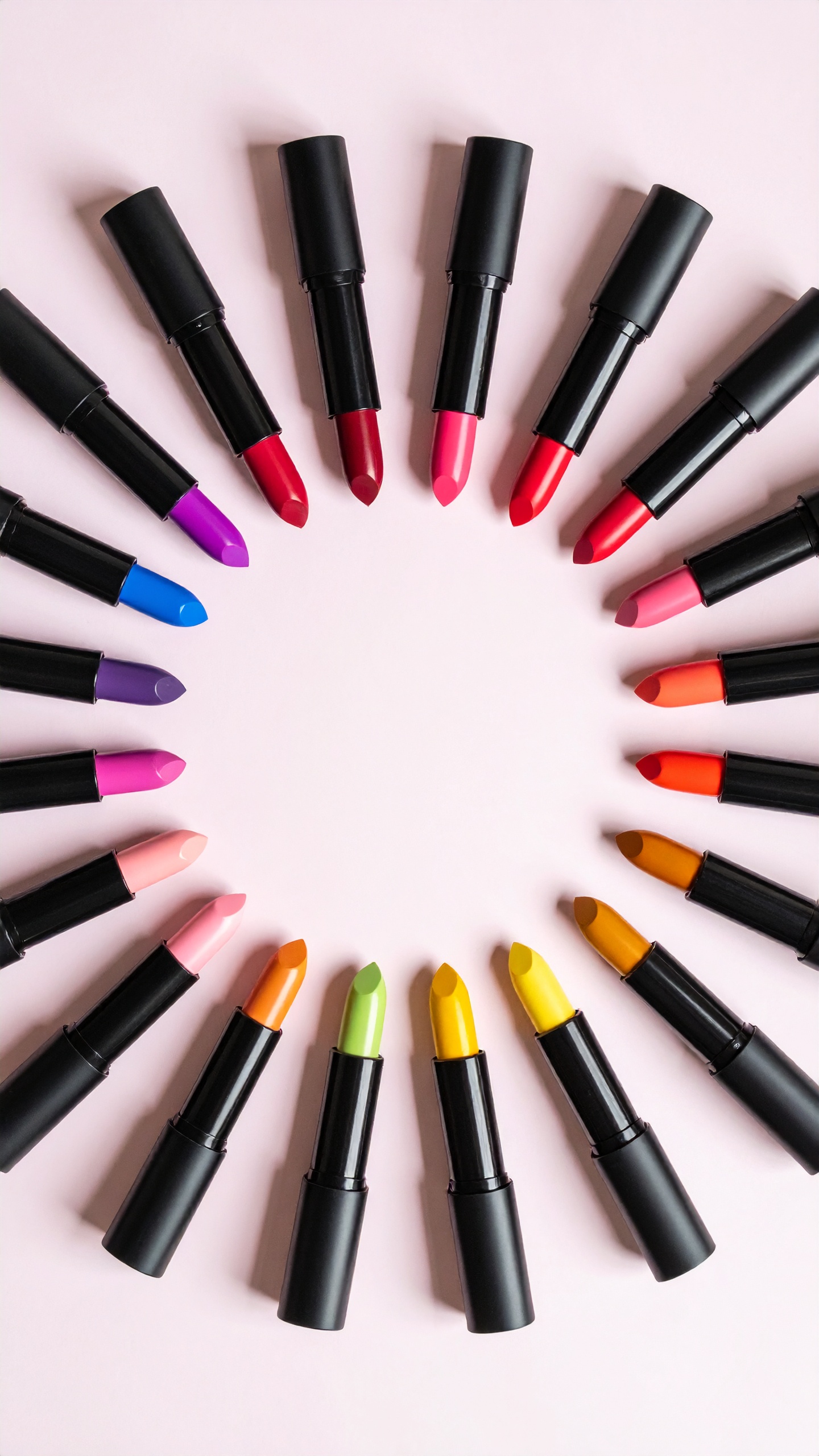 A vibrant array of lipsticks arranged in a circle on a soft pink background showcases