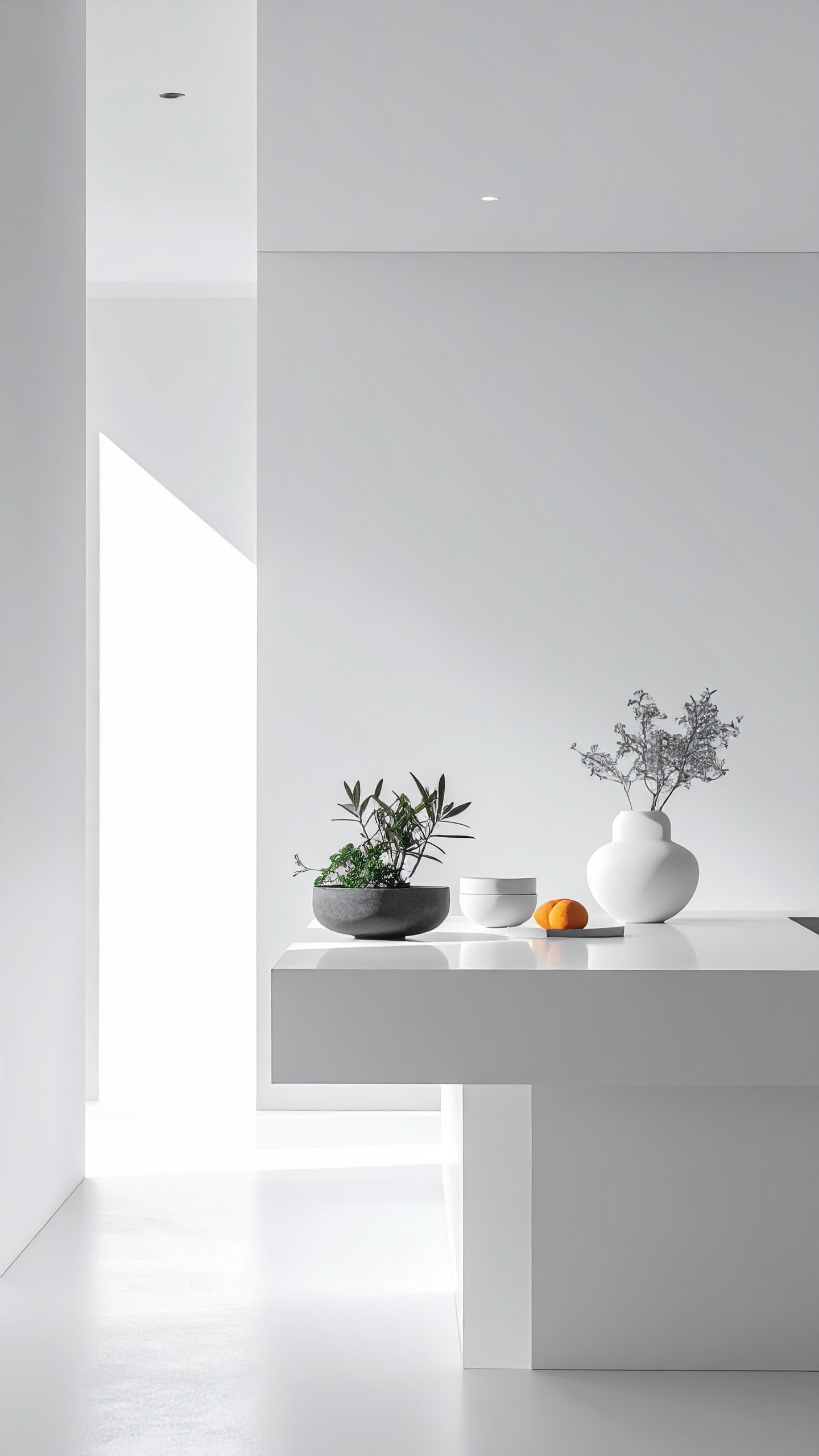 A minimalist white interior features a sleek table adorned with simple decor