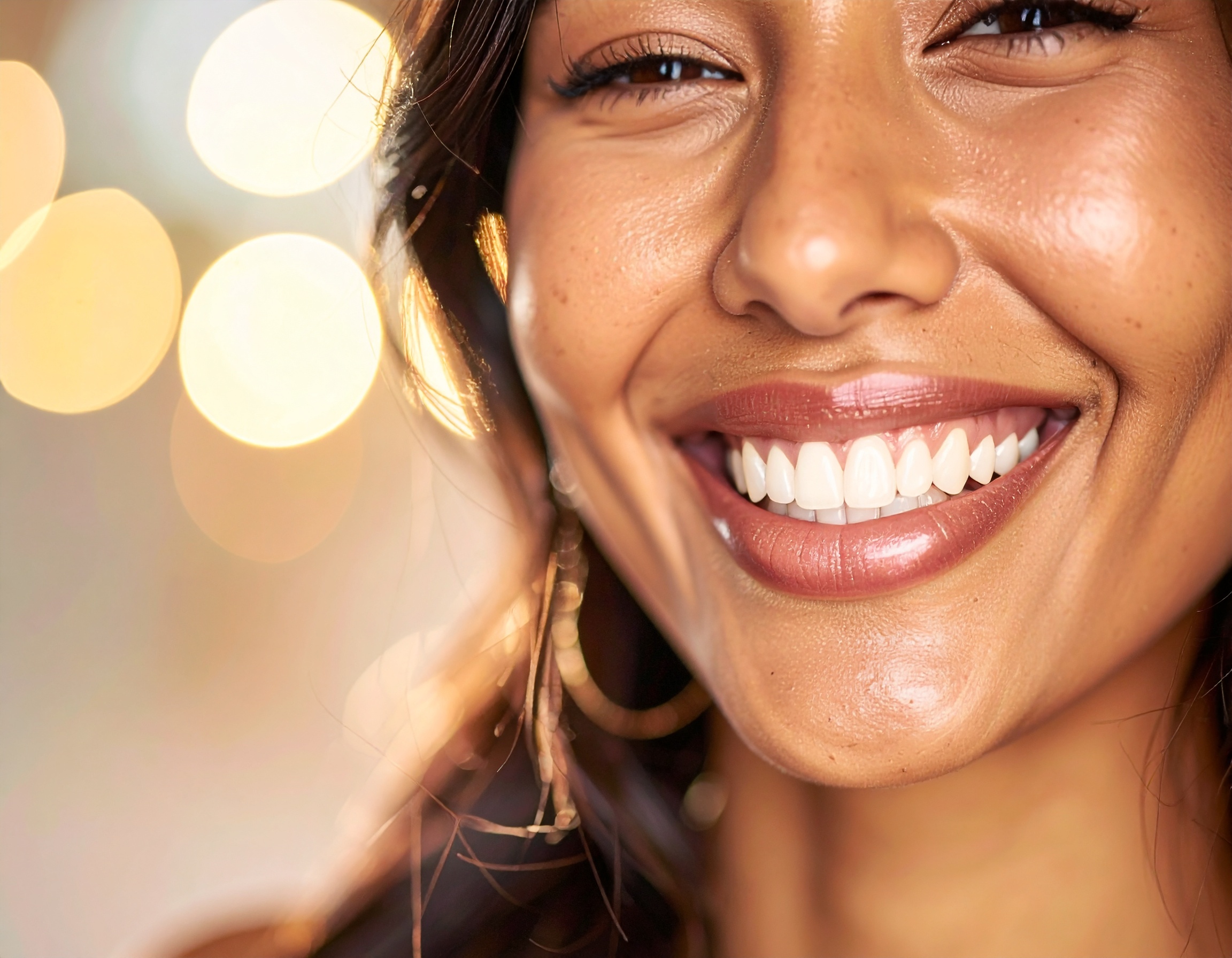 A radiant smile with flawless white teeth shines against a warm, blurred background