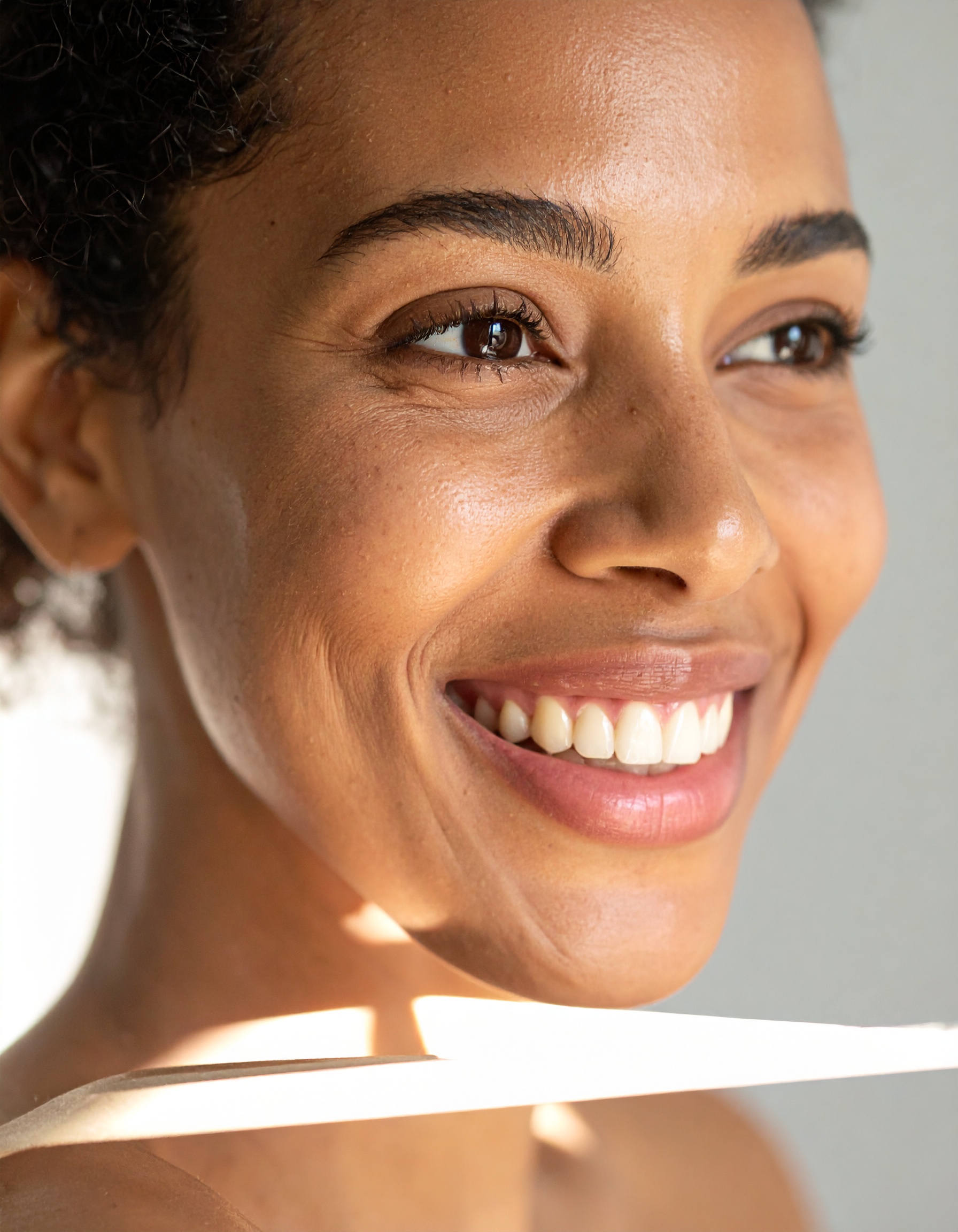 A radiant smile is highlighted with natural lighting on a person's face