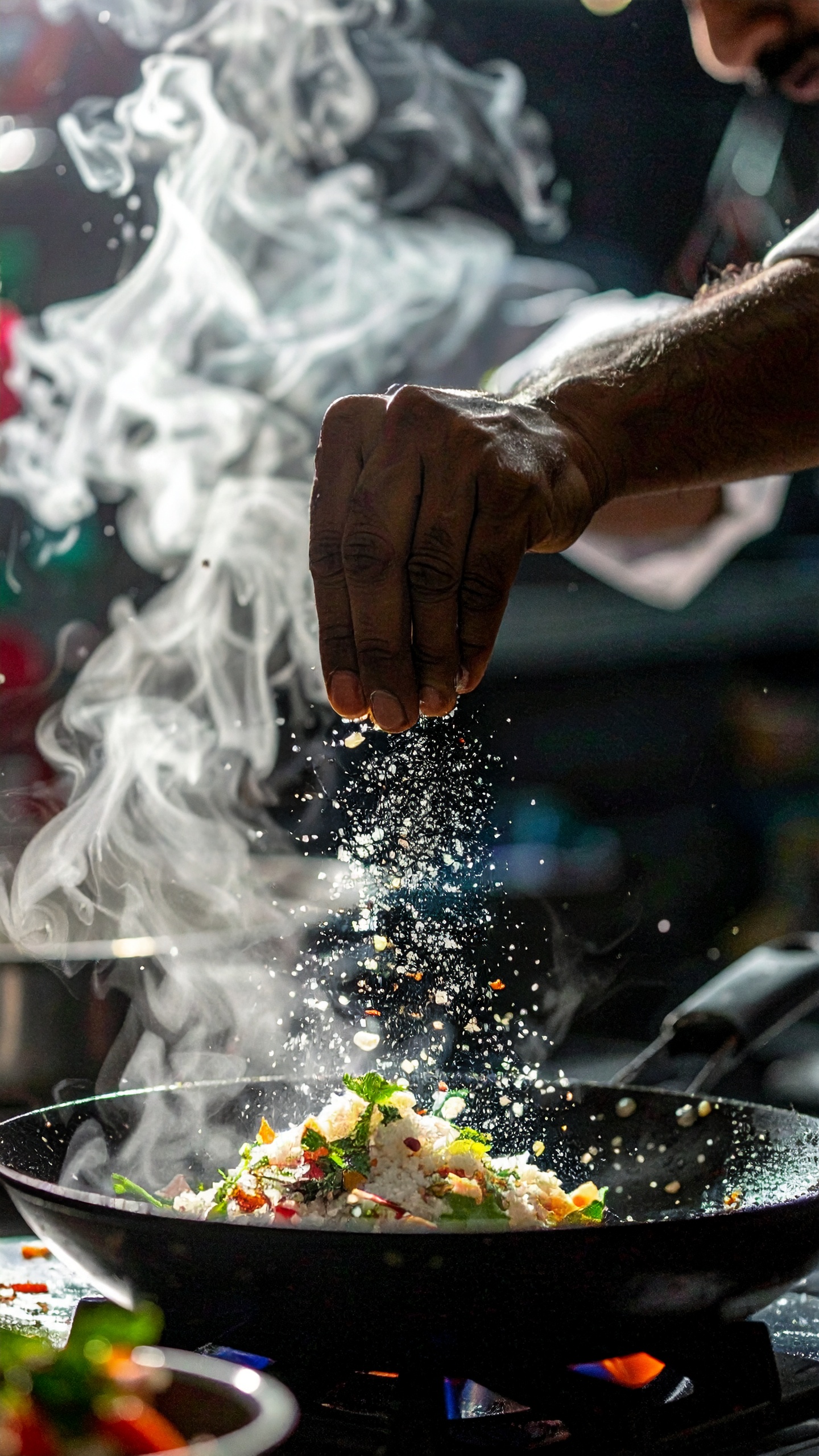 A chef skillfully sprinkles spices over a sizzling dish in a pan