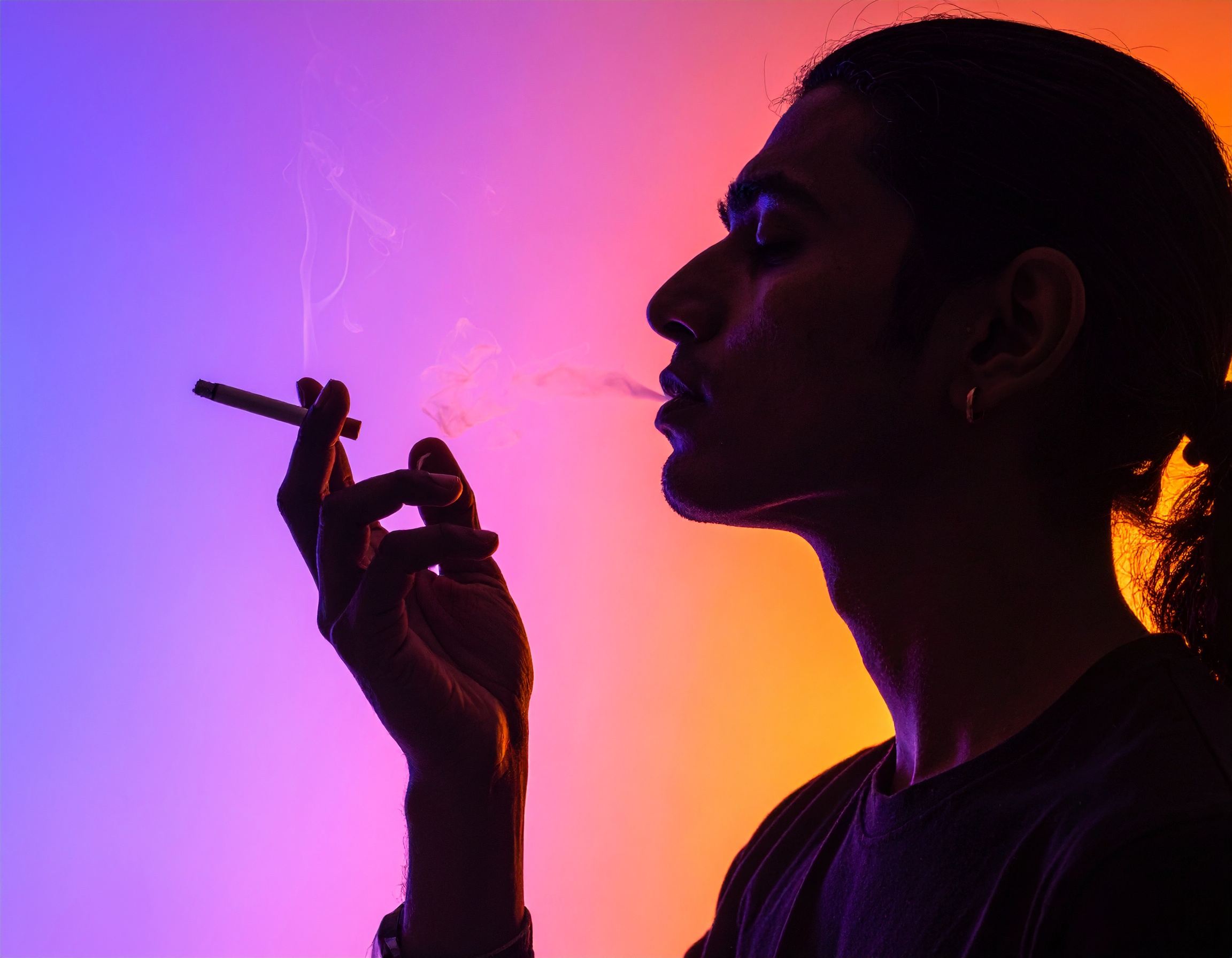 Silhouette of a person smoking against a vibrant, colorful background