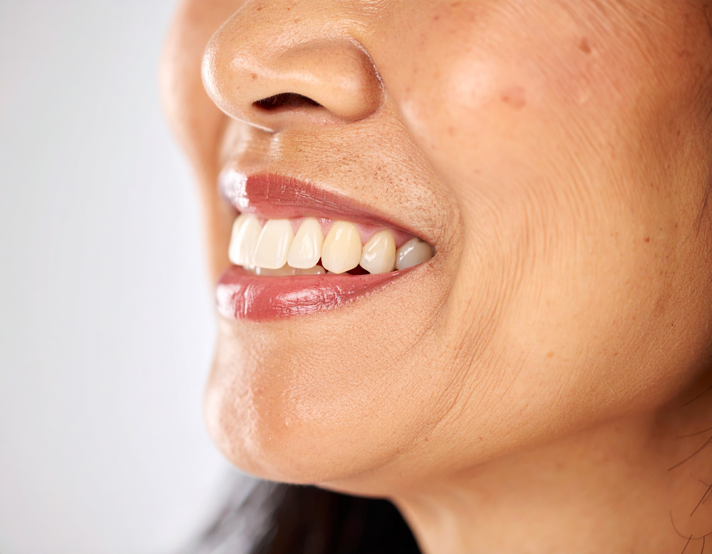 A close-up of a smiling woman with well-maintained teeth and radiant skin