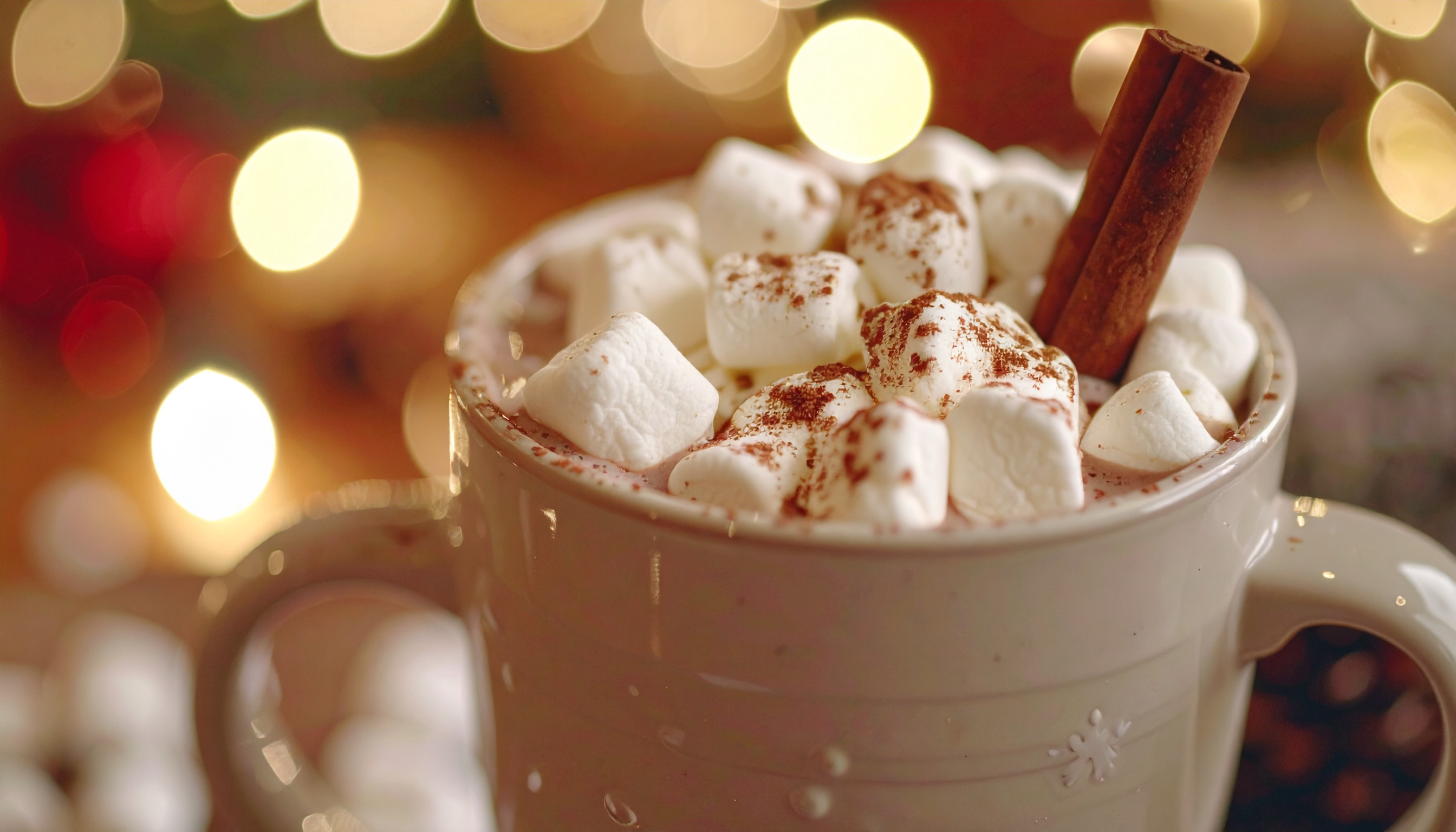 Caneca de chocolate quente com marshmallows e canela em um ambiente aconchegante de Natal, com luzes suaves e bokeh brilhante, transmitindo calor e conforto.