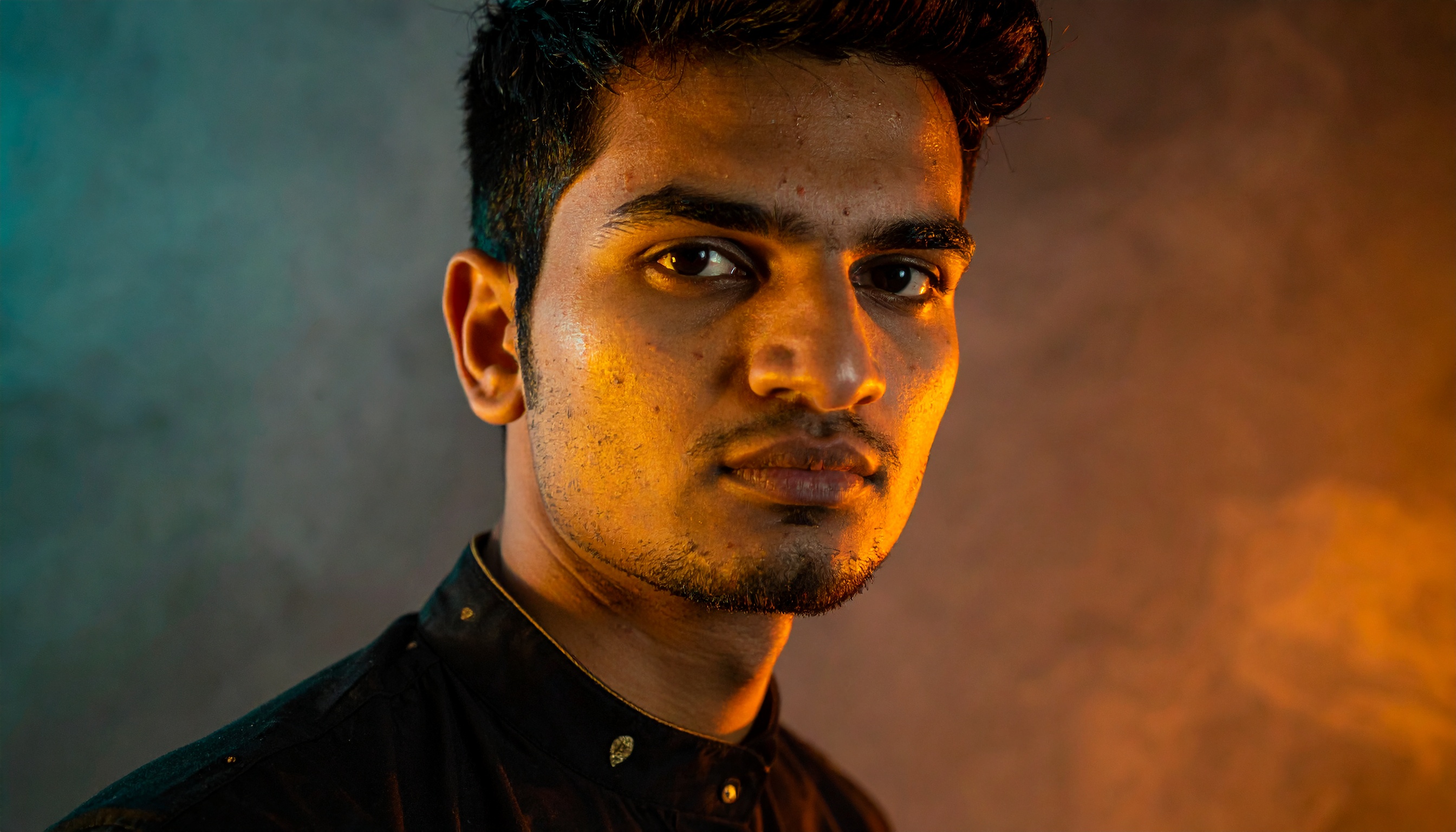 A young man gazes intently with warm, dramatic lighting highlighting his features