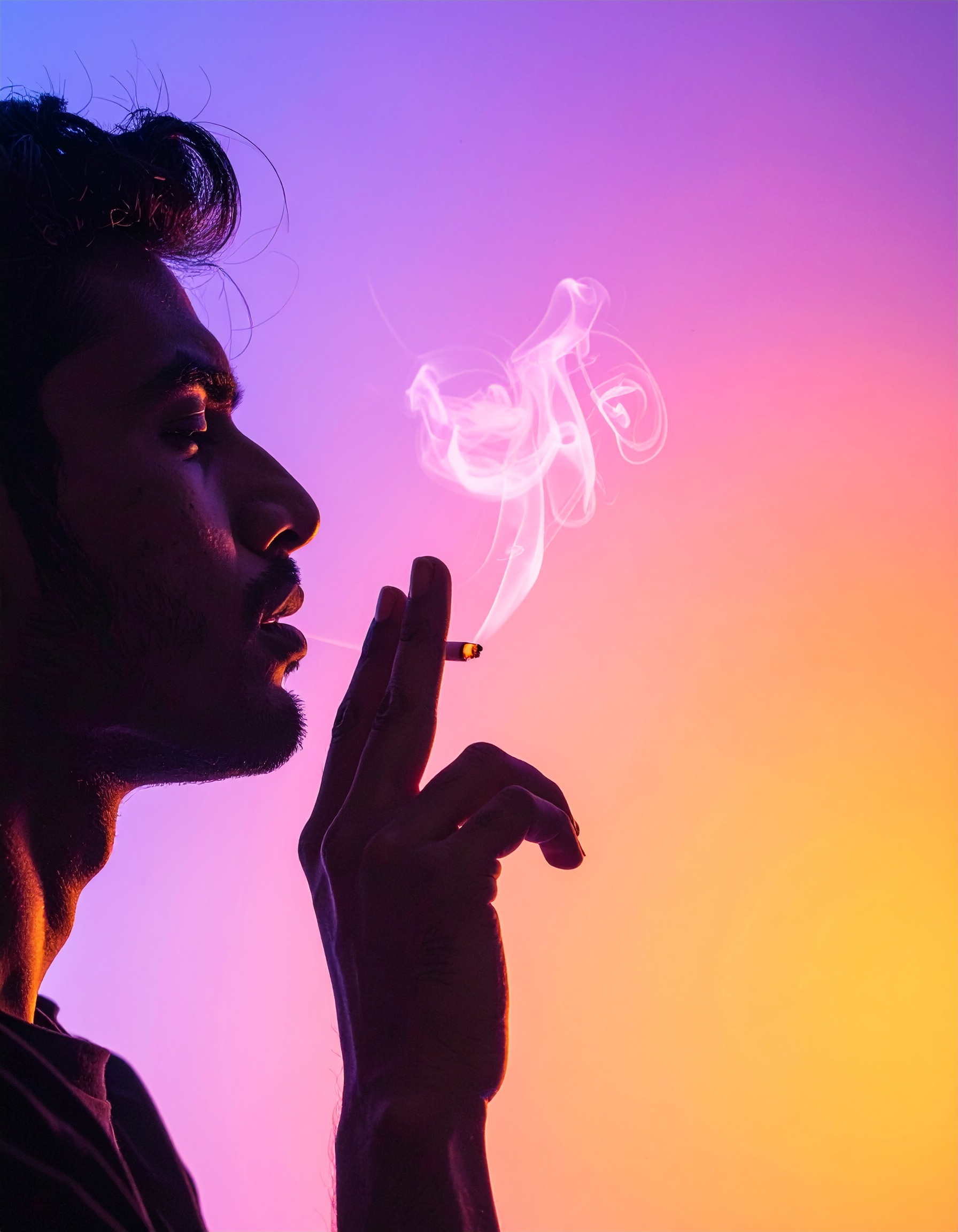 A silhouette of a person smoking against a vibrant gradient background