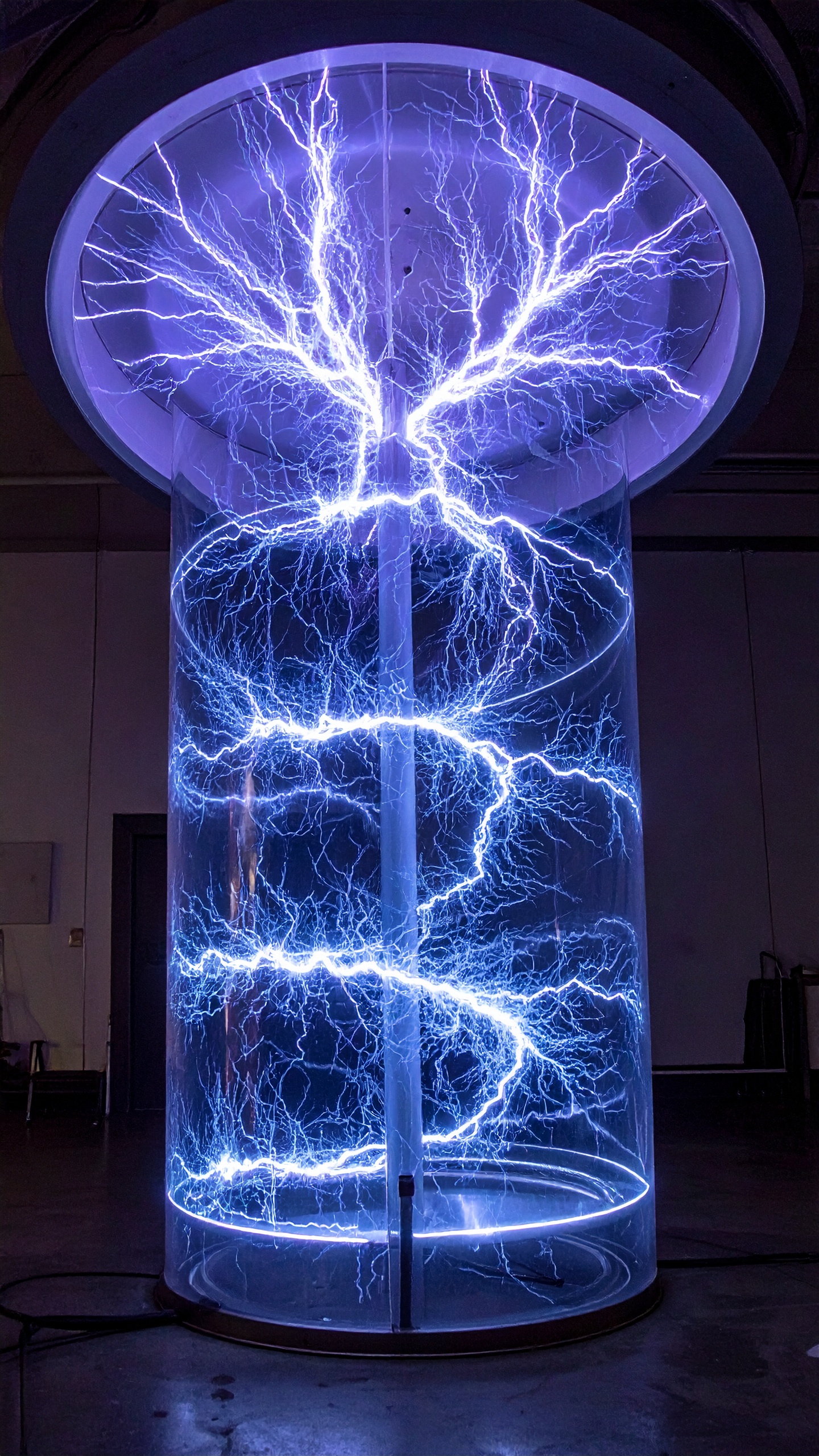 A captivating Tesla coil display emits vivid blue electrical arcs within a transparent cylinder
