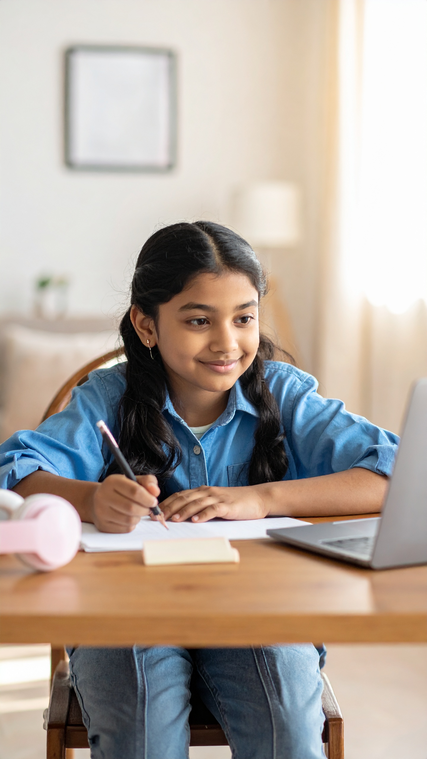 A young girl is engaged in online learning at a desk with a laptop