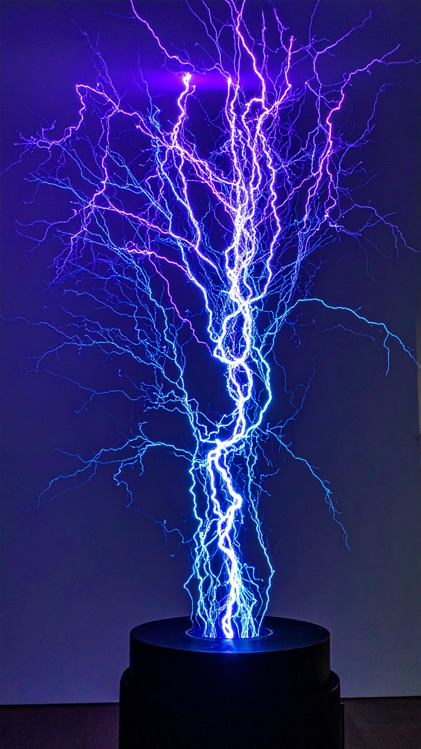 A vivid display of electric blue and purple lightning illuminates the dark background