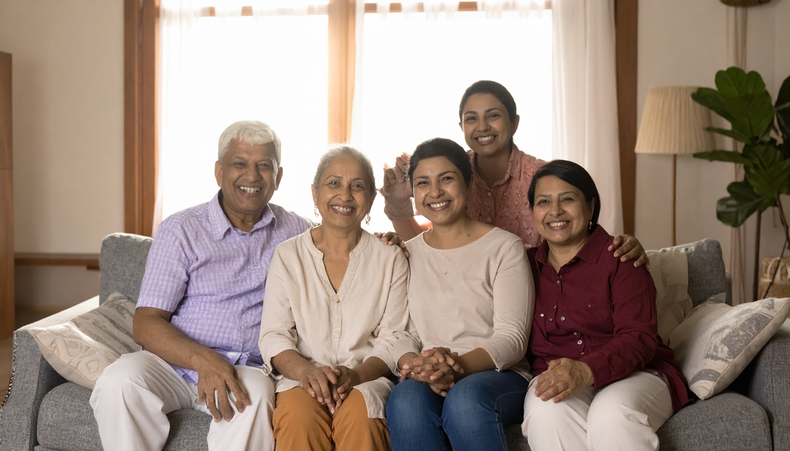 A family of five sits together on a comfortable sofa, sharing smiles and joy