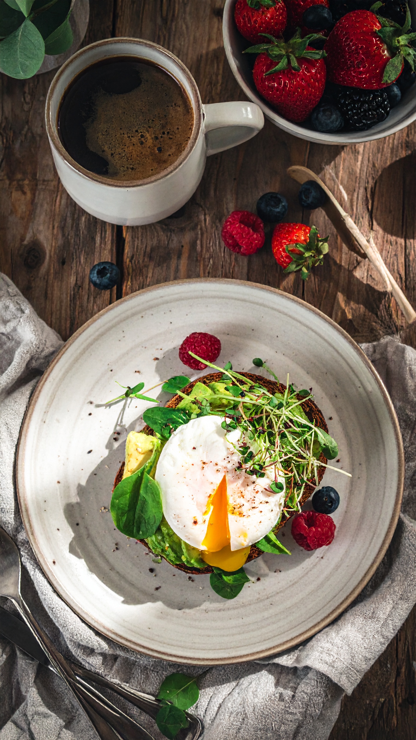 A hearty breakfast featuring a poached egg atop avocado toast is served with a fresh