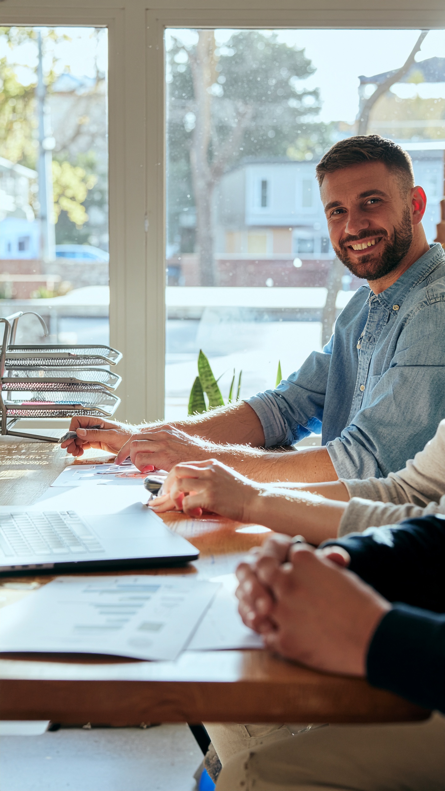 A group of professionals engaged in a meeting at a sunlit office table